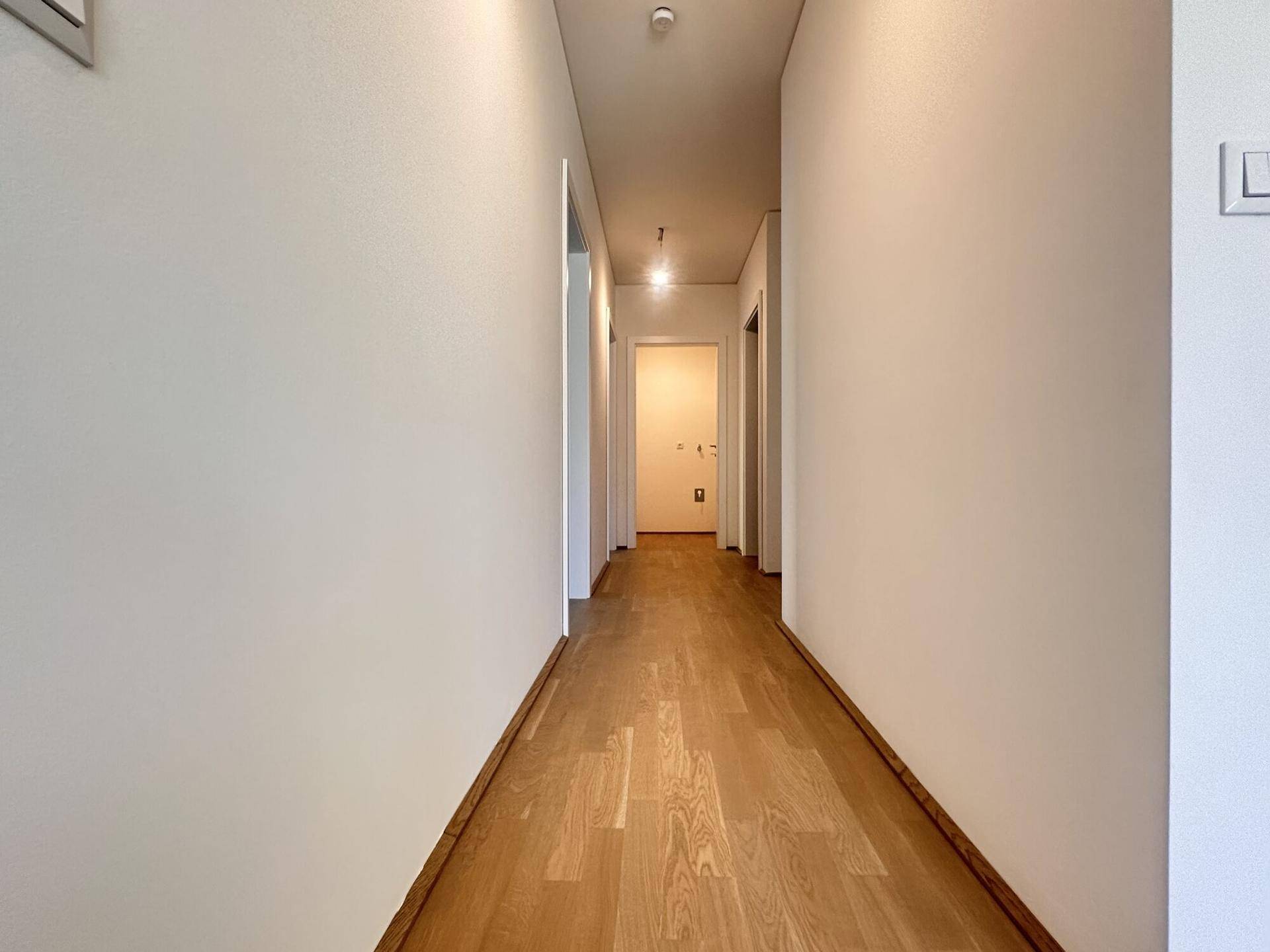 Heller Flur mit Parkettboden, der zu den verschiedenen Zimmern der Wohnung führt.
