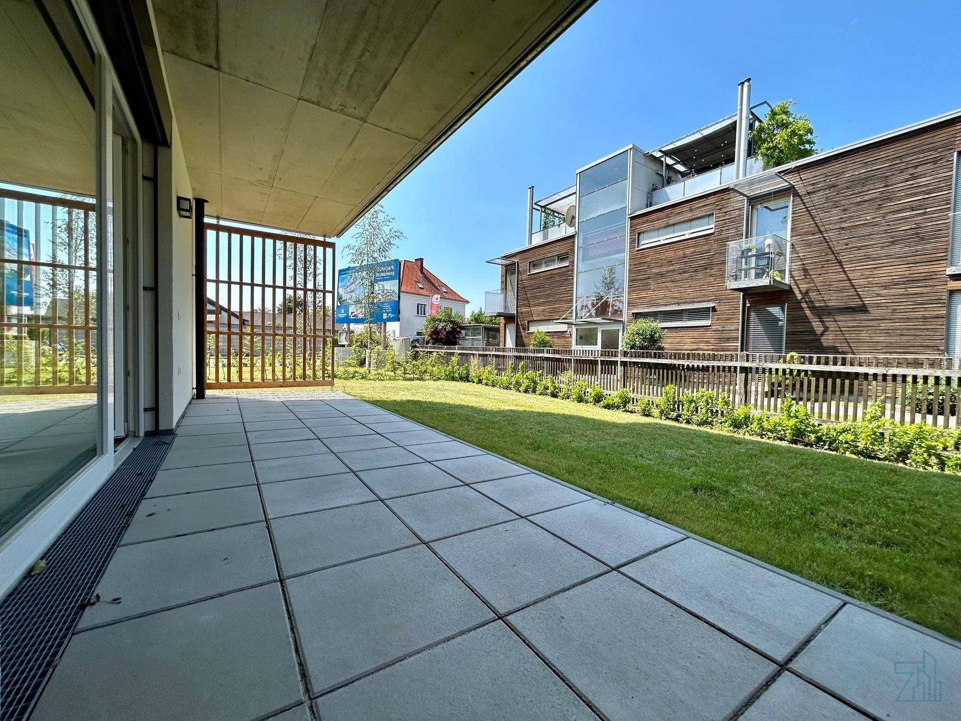 Geräumige Terrasse mit Steinplatten und angrenzender Rasenfläche, ideal für Entspannung.
