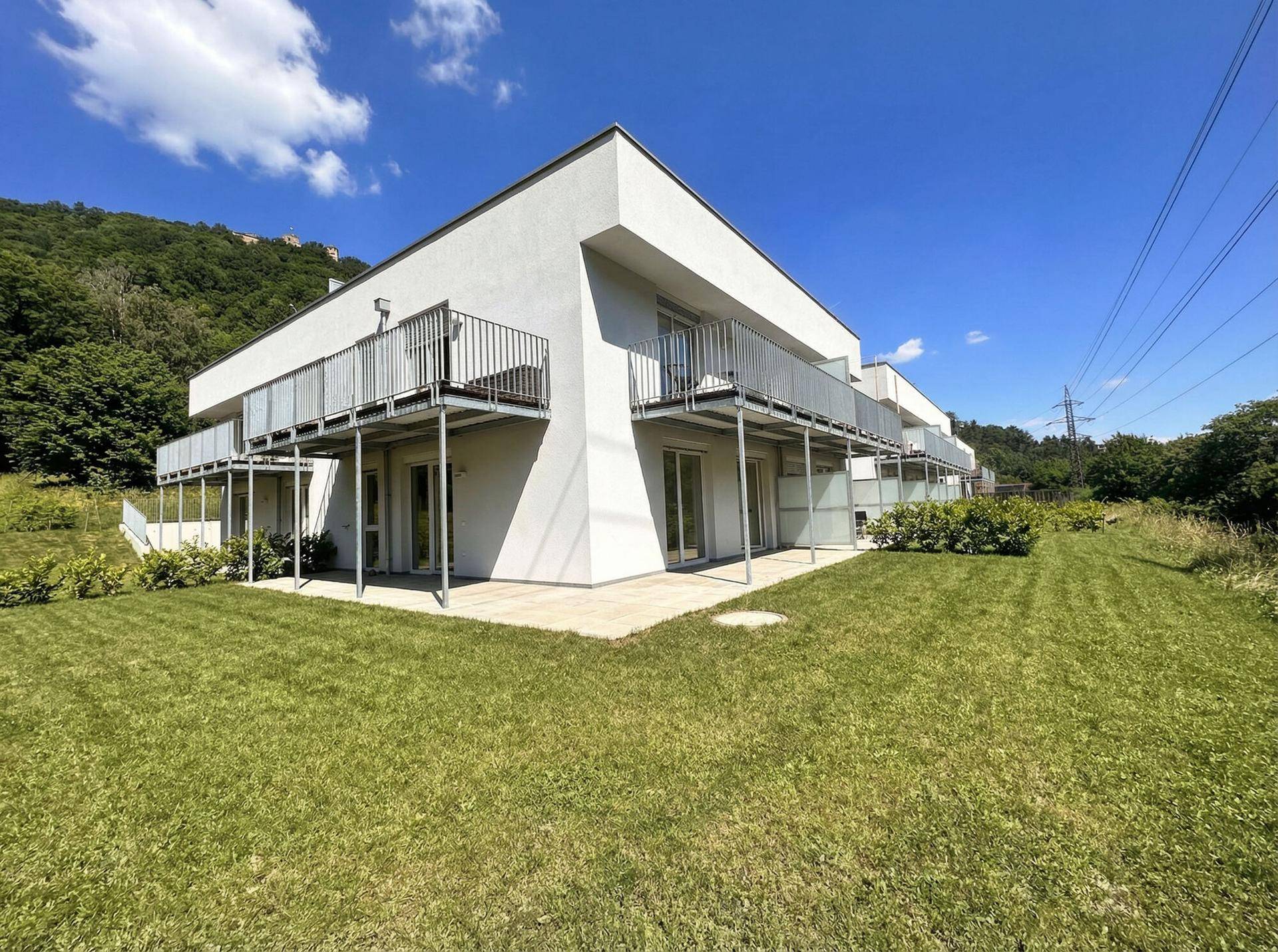 Moderne Wohngebäude mit großzügigen Rasenflächen und Balkonen im Erdgeschoss.