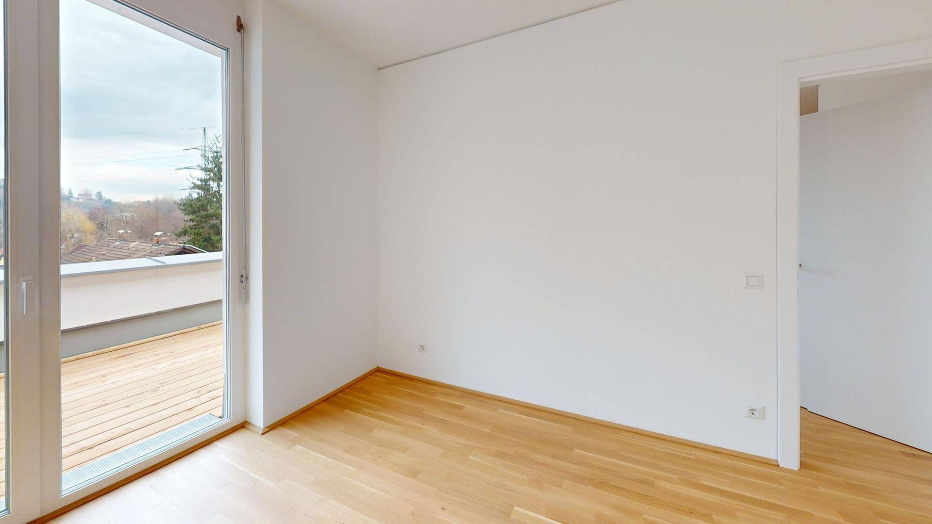 Helles Schlafzimmer mit Holzboden und direktem Zugang zur Terrasse.