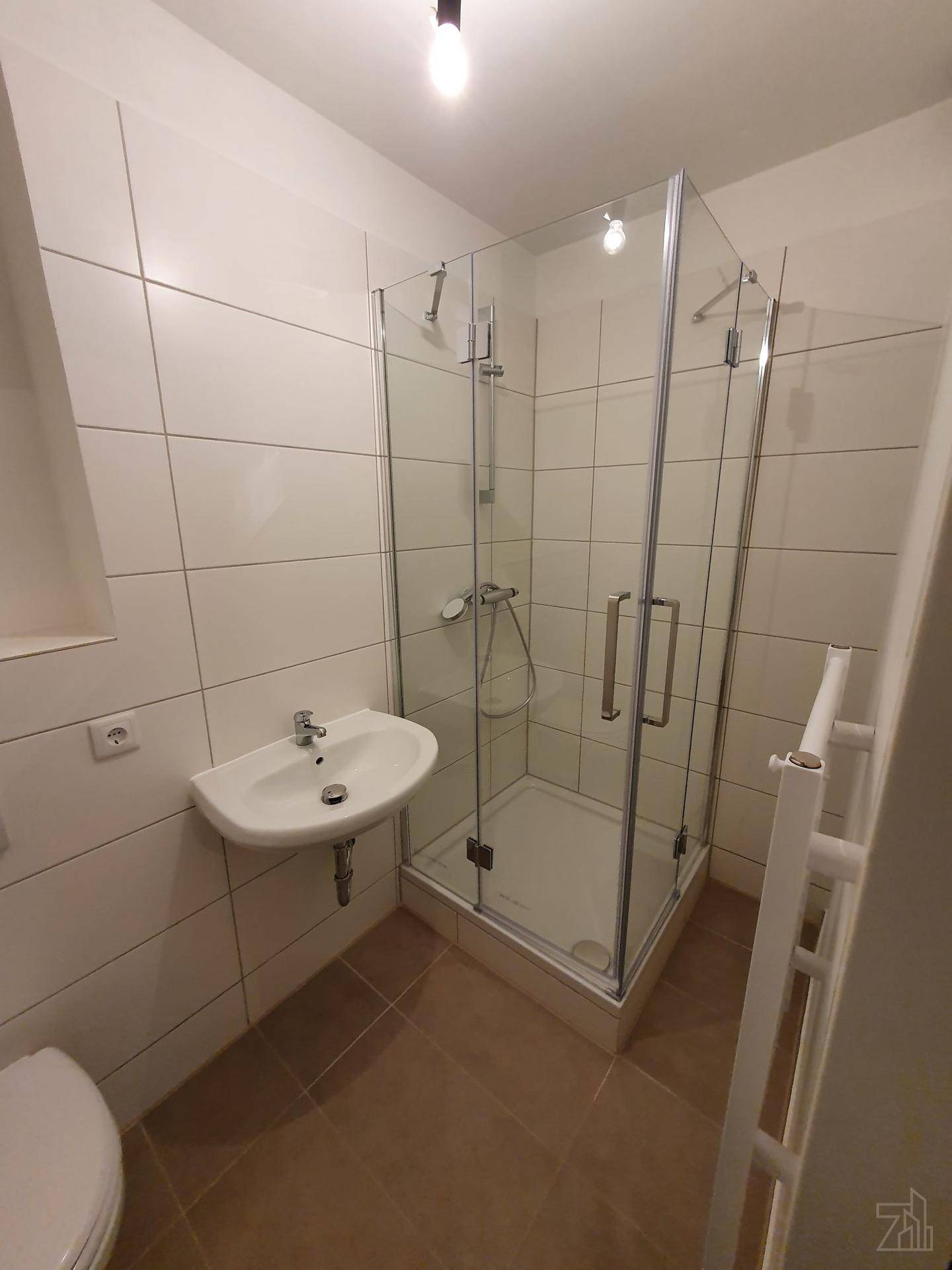 Modernes Badezimmer mit Duschkabine, Waschbecken und weißen Fliesen.