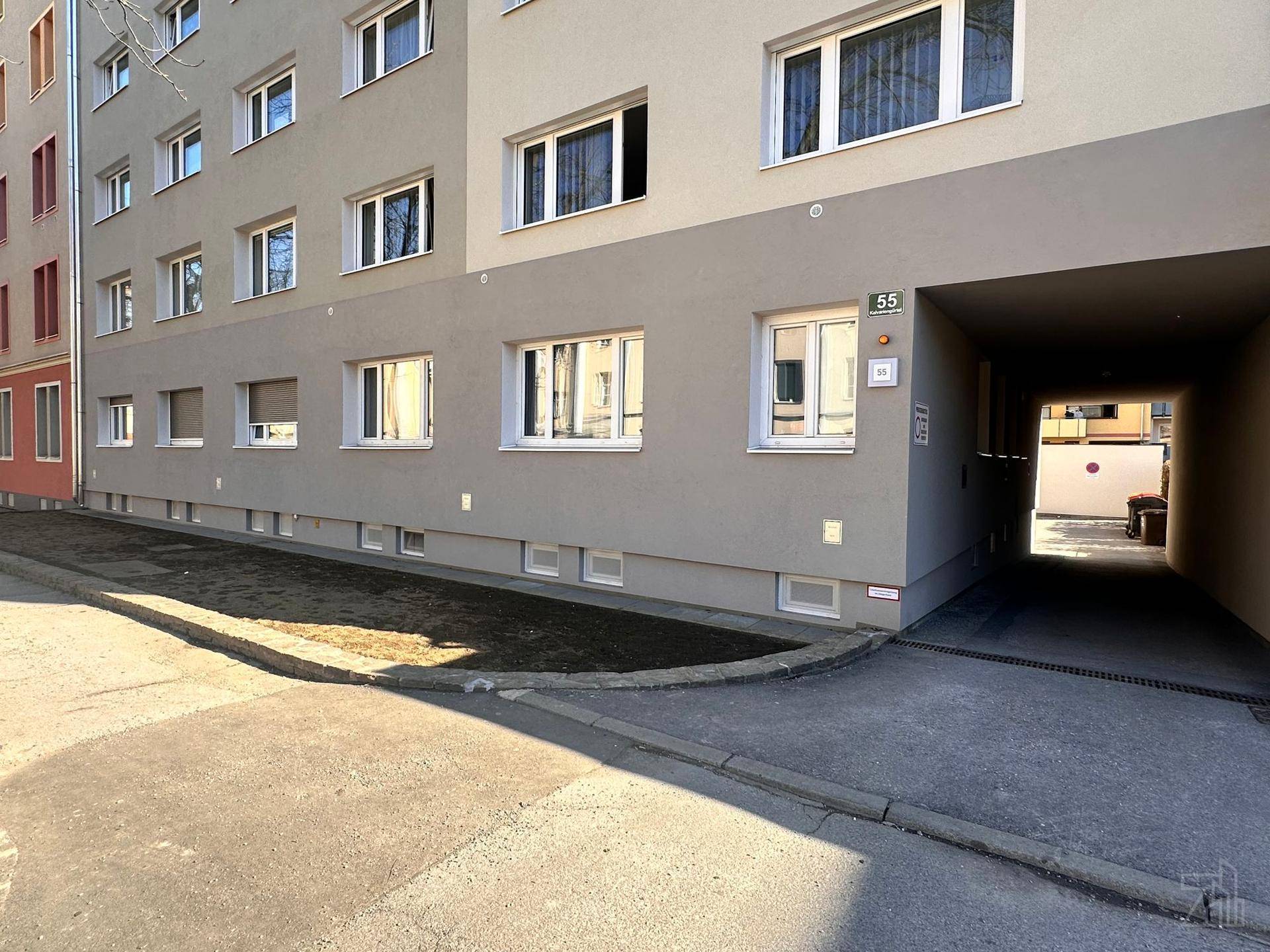 Erdgeschossfassade eines Wohngebäudes mit Eingangsbereich und kleinen Fenstern.