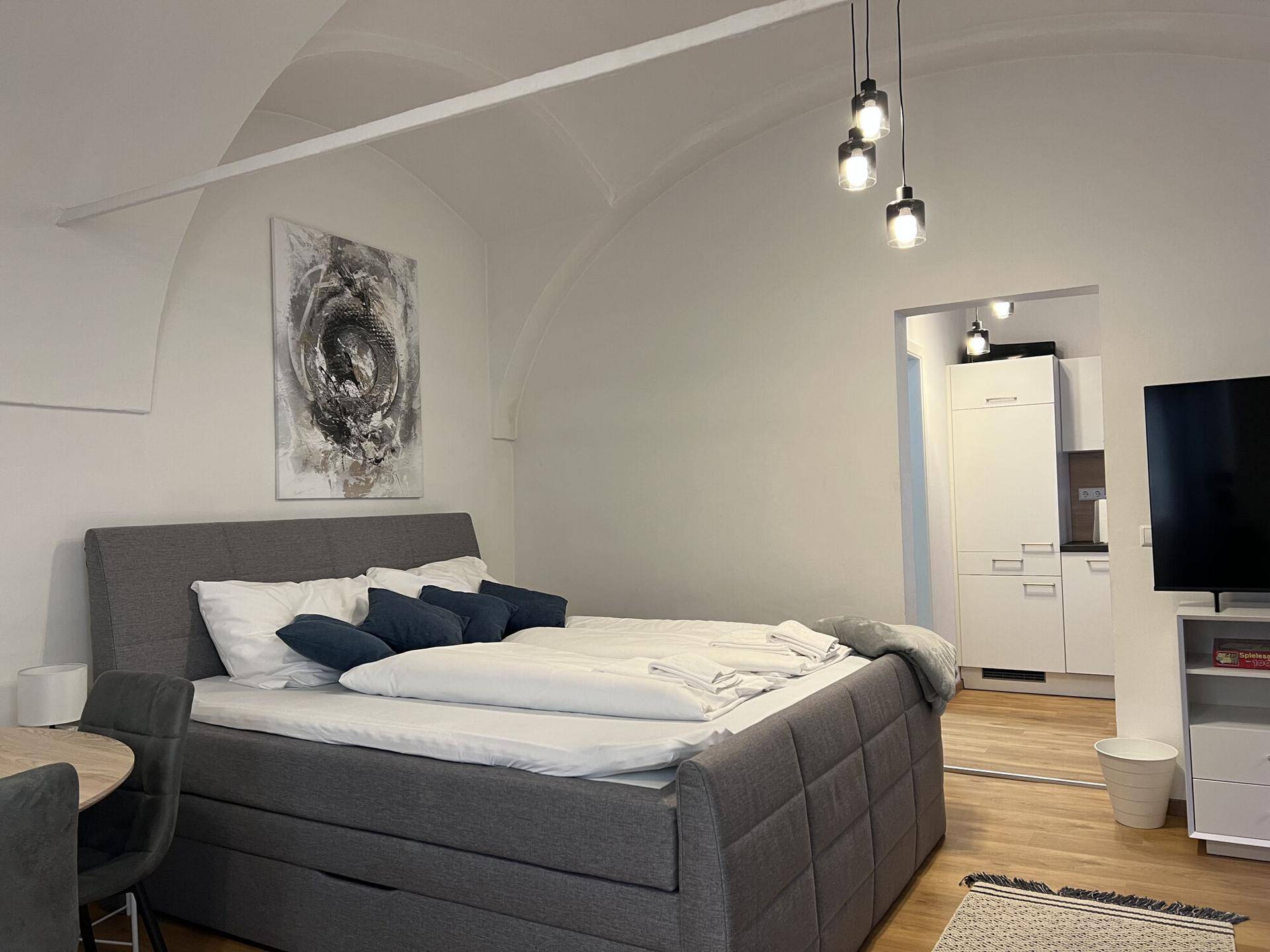 Gemütliches Schlafzimmer mit Doppelbett, Gewölbedecke und moderner Beleuchtung.
