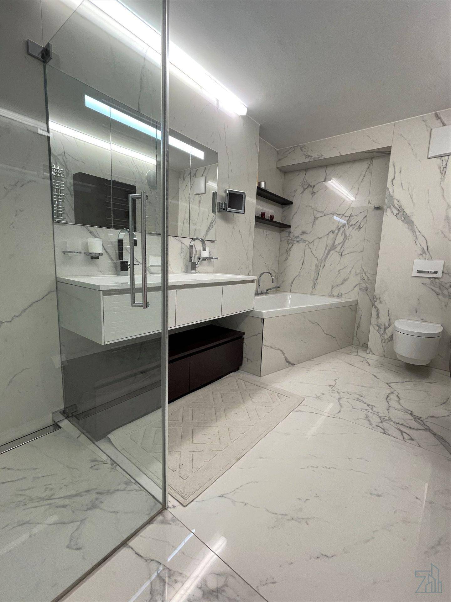 Luxuriöses Badezimmer mit Marmorfliesen, begehbarer Dusche, Doppelwaschbecken und Badewanne.