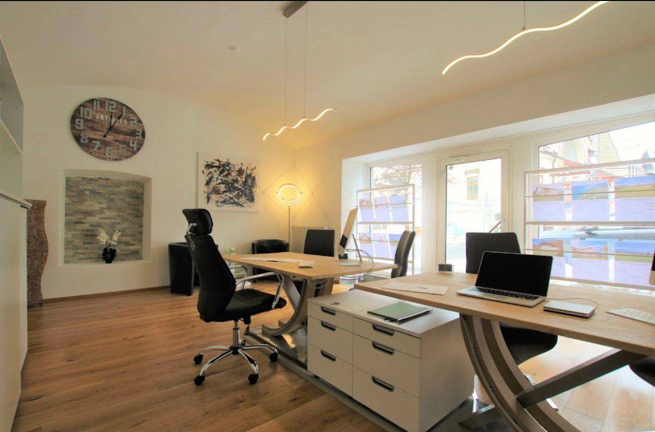 Helles und modernes Büro mit Holzboden, großen Fenstern und stilvoller Beleuchtung.