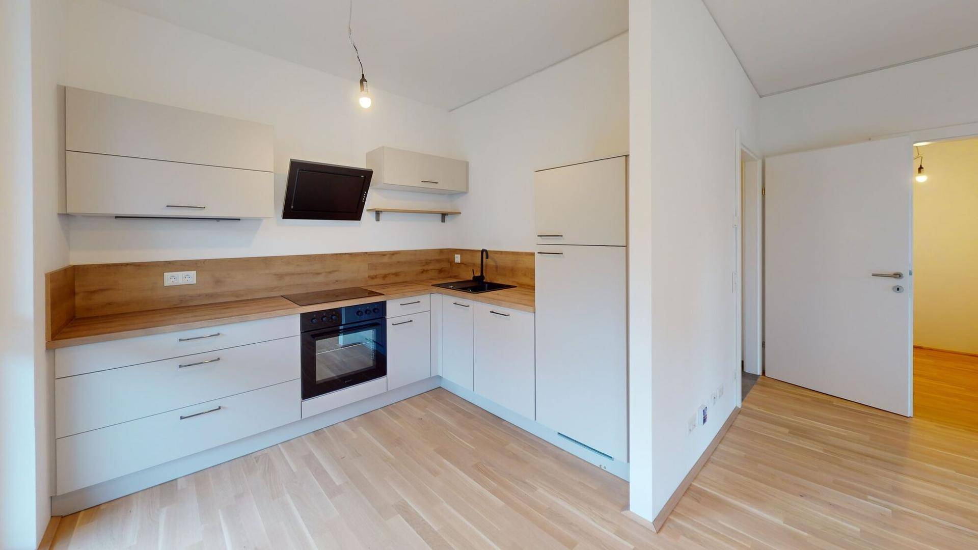 Moderne Einbauküche mit hellen Schränken, Holzarbeitsplatte und integrierten Geräten.