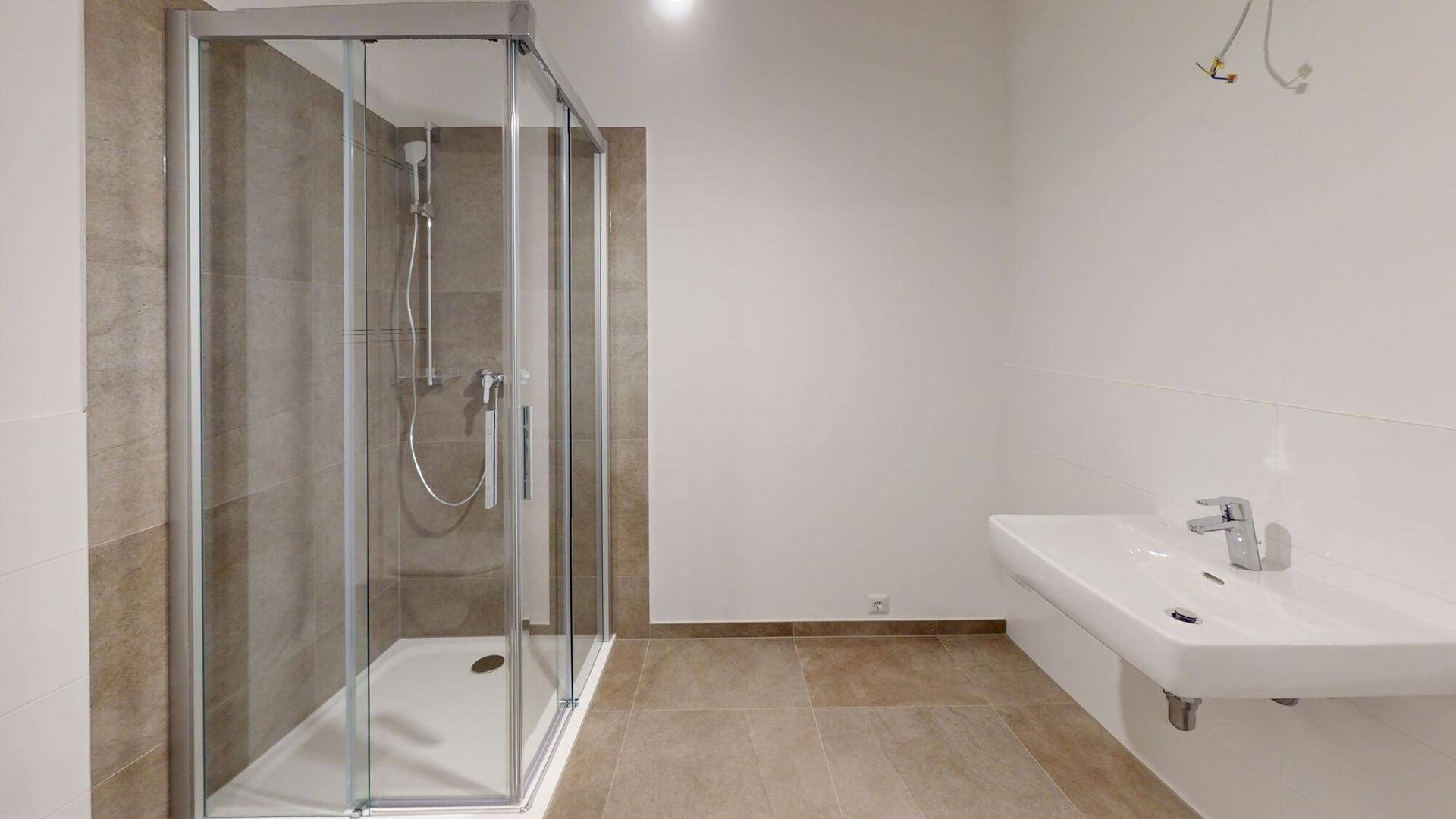 Modernes Badezimmer mit Duschkabine aus Glas und einem wandmontierten Waschbecken.