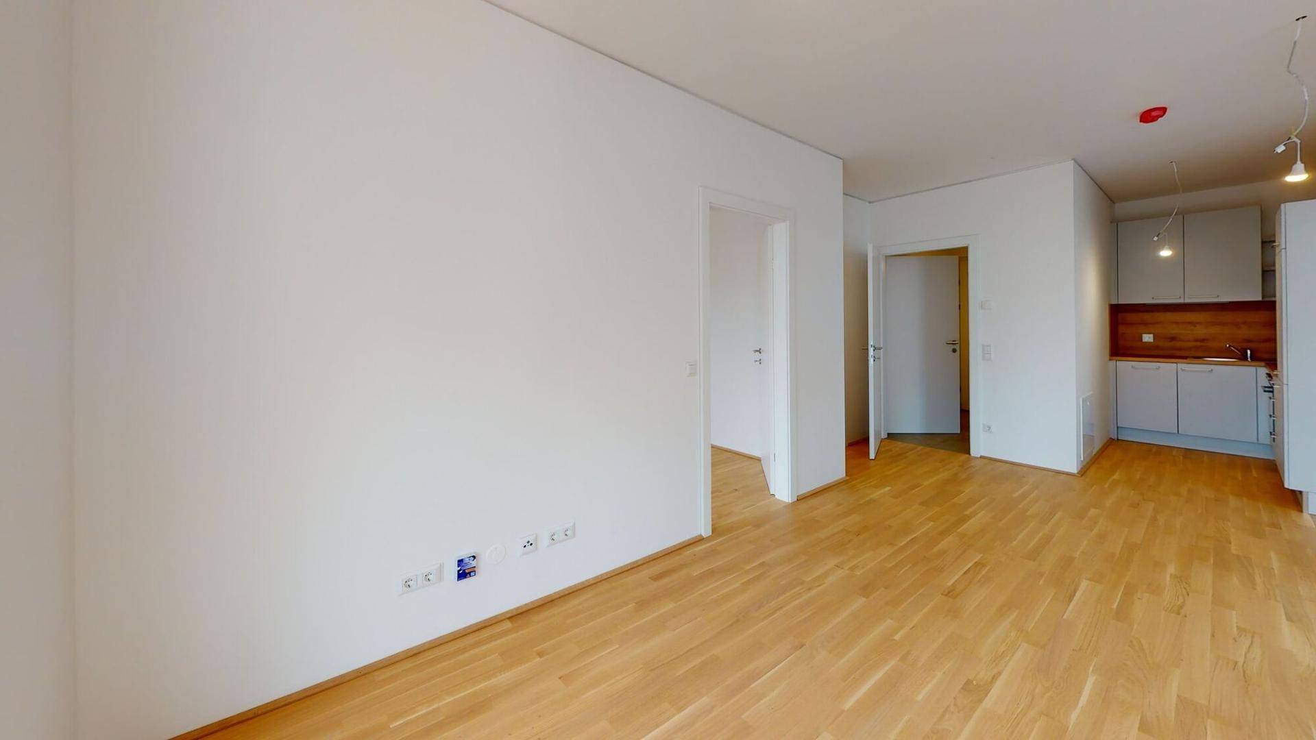 Offener Wohnbereich mit Parkettboden und Blick auf die angrenzende Küche.