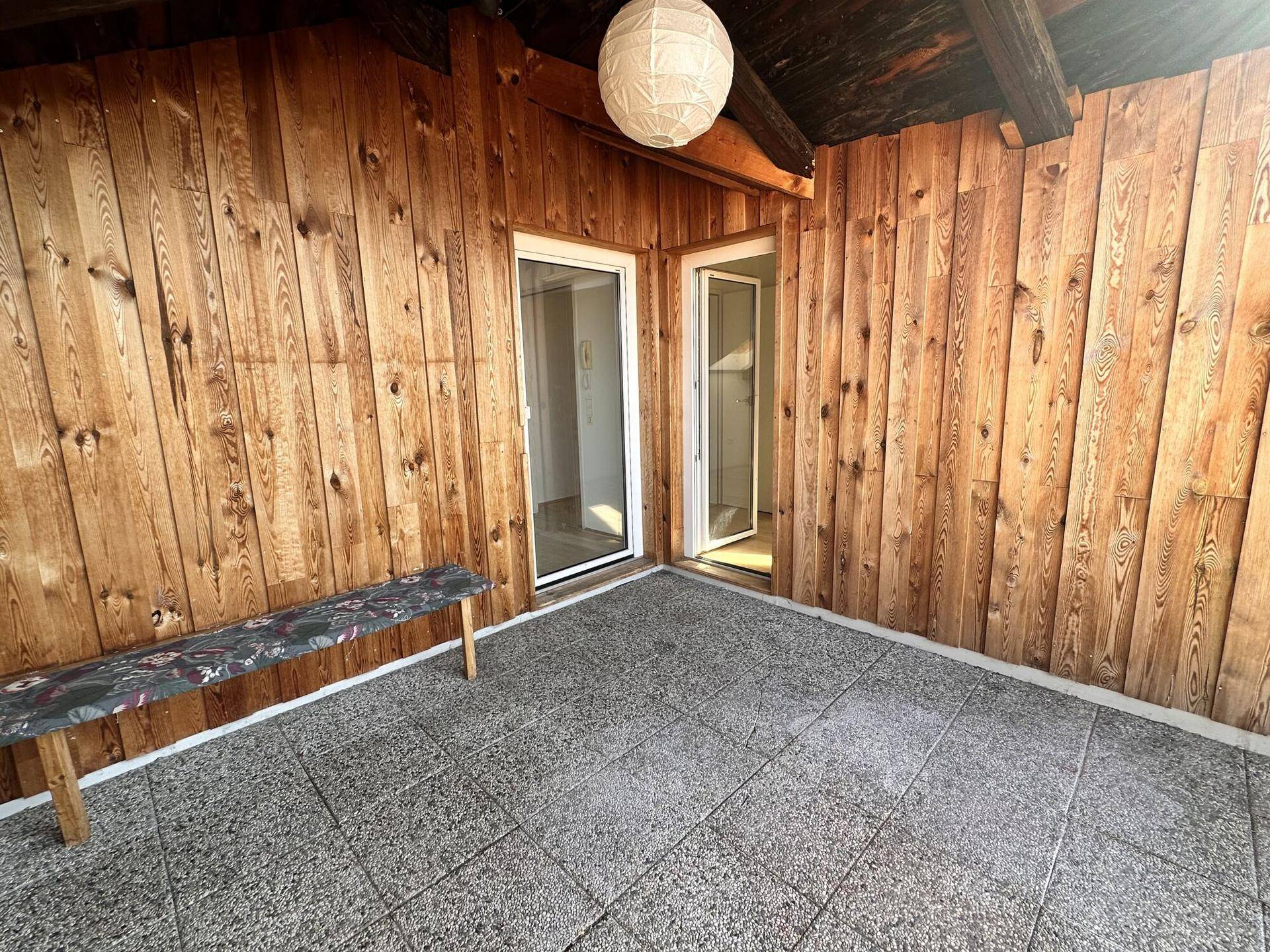 Geräumiger Balkon mit Holzwänden und Zugang zu den Innenräumen.