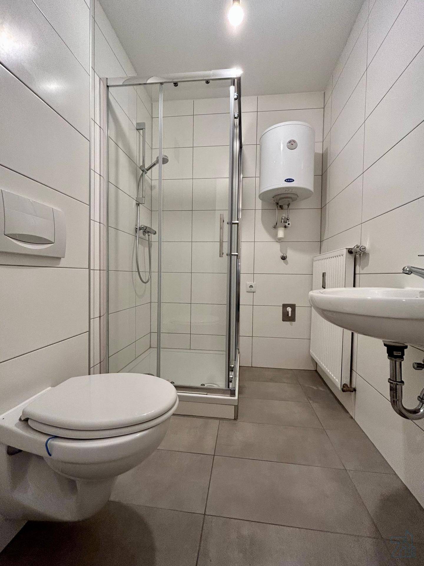 Modernes Badezimmer mit weißen Fliesen, Dusche, WC und Waschbecken.
