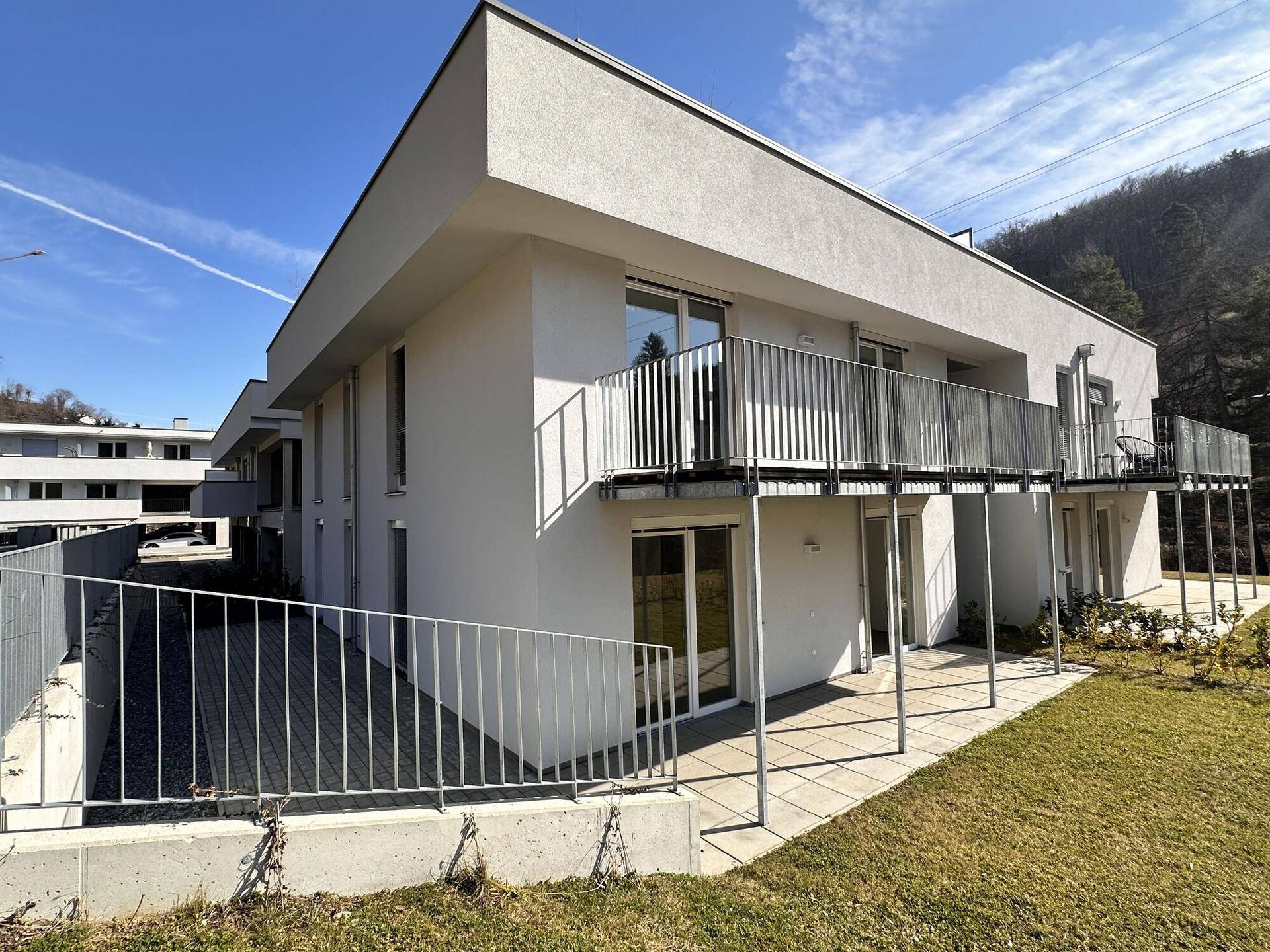 Moderne Architektur eines Neubaus mit Balkonen, Terrassen und gepflegter Grünfläche.