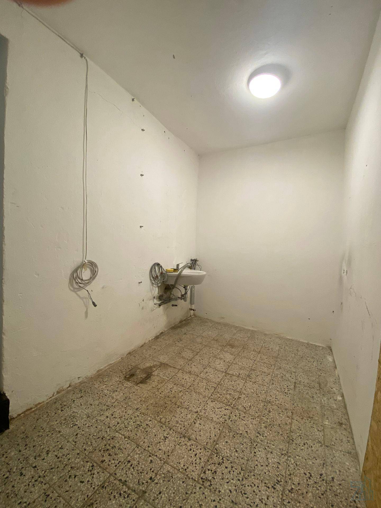 Kleiner Hauswirtschaftsraum mit Waschbecken und Fliesenboden, ideal für Reinigungsarbeiten.