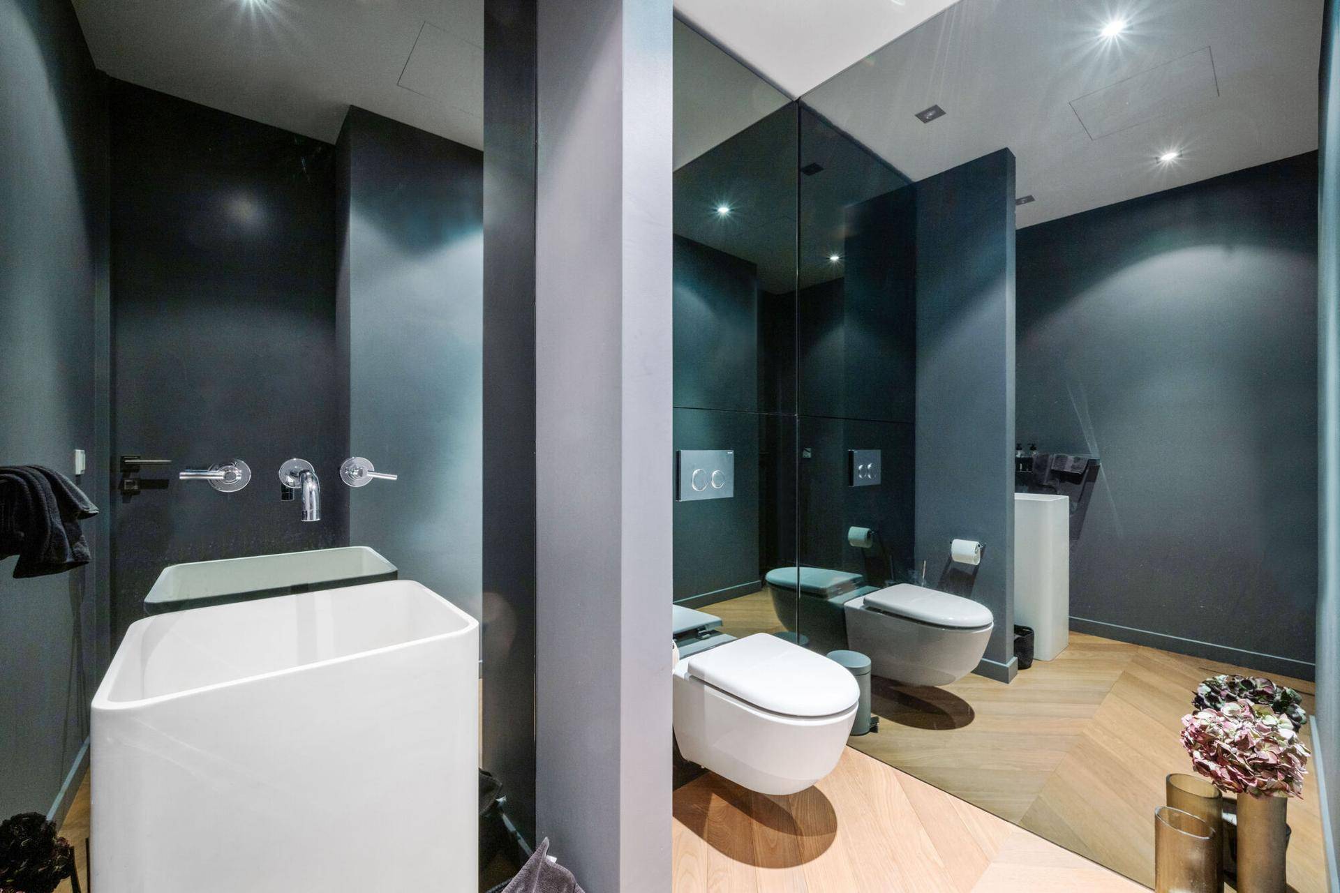 Modernes Gäste-WC mit dunklen Wänden, stilvollem Waschbecken und Wand-WC.