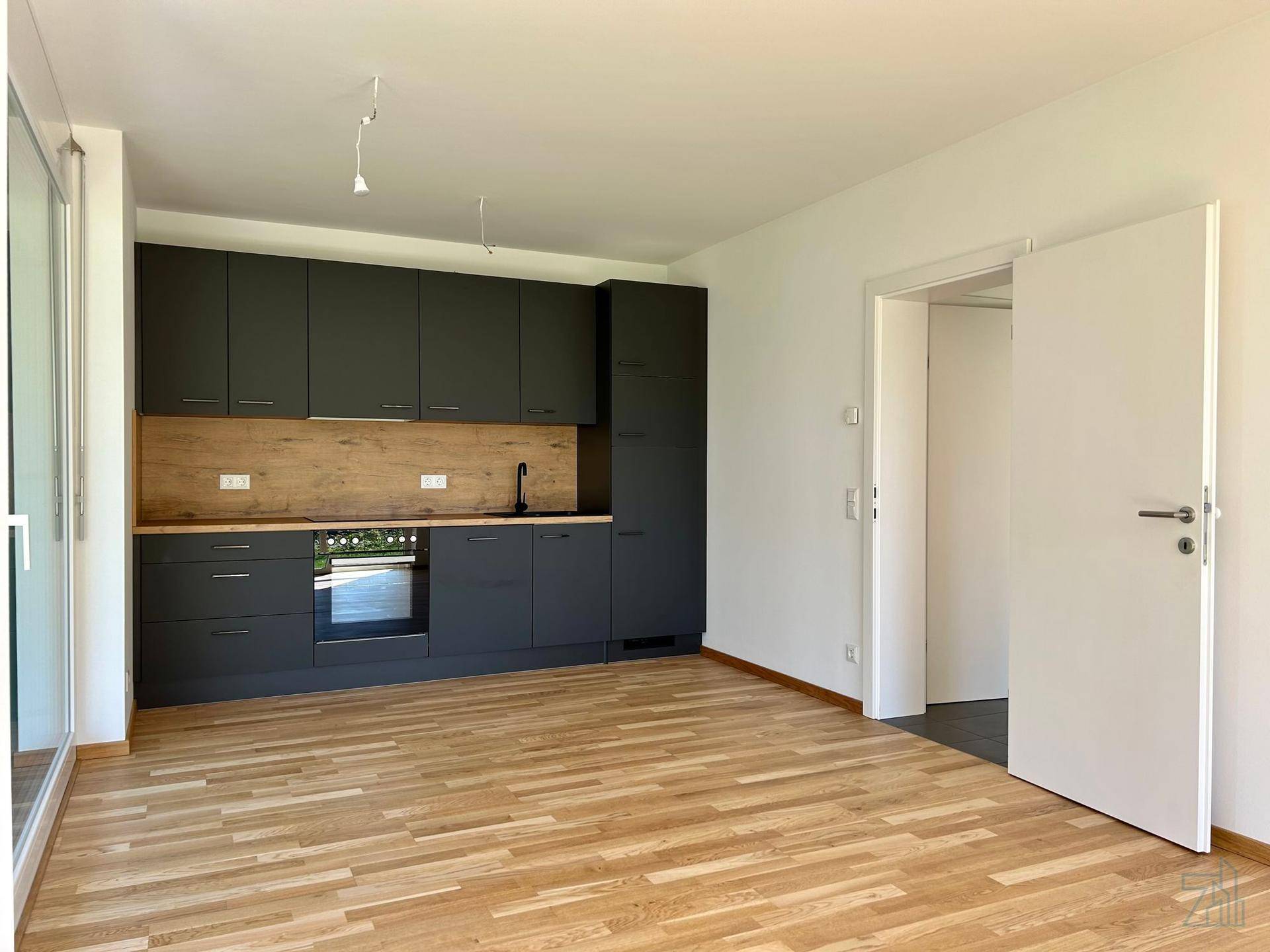 Offener Wohnbereich mit integrierter Küche, Holzboden und viel Tageslicht.