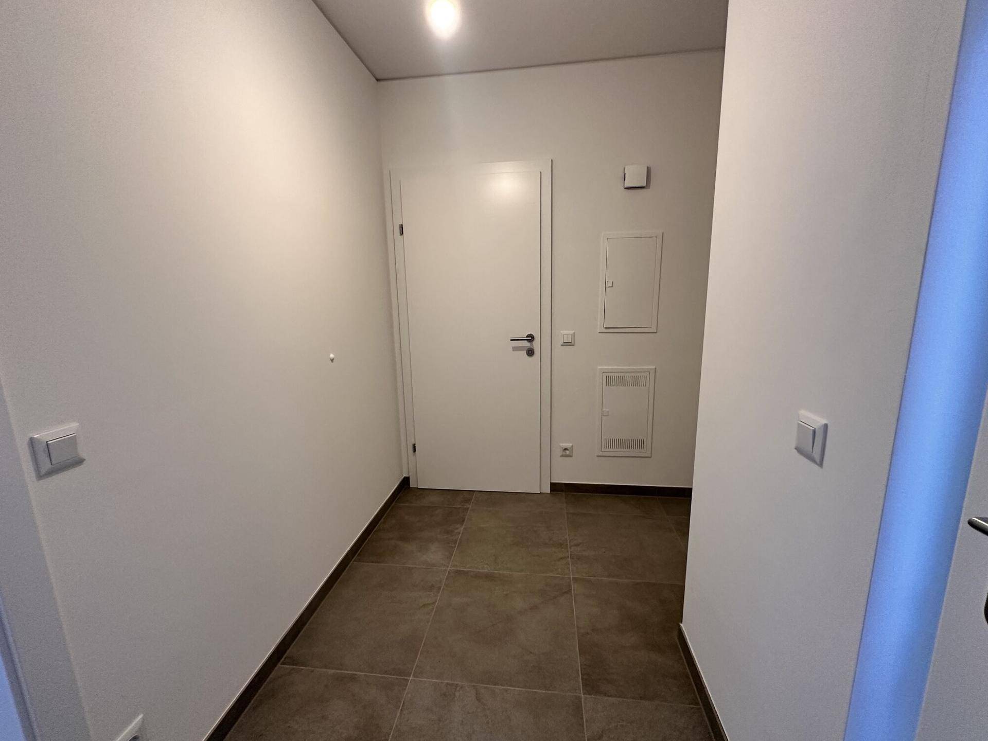 Heller Eingangsbereich mit Fliesenboden und weißen Wänden, modern und einladend gestaltet.