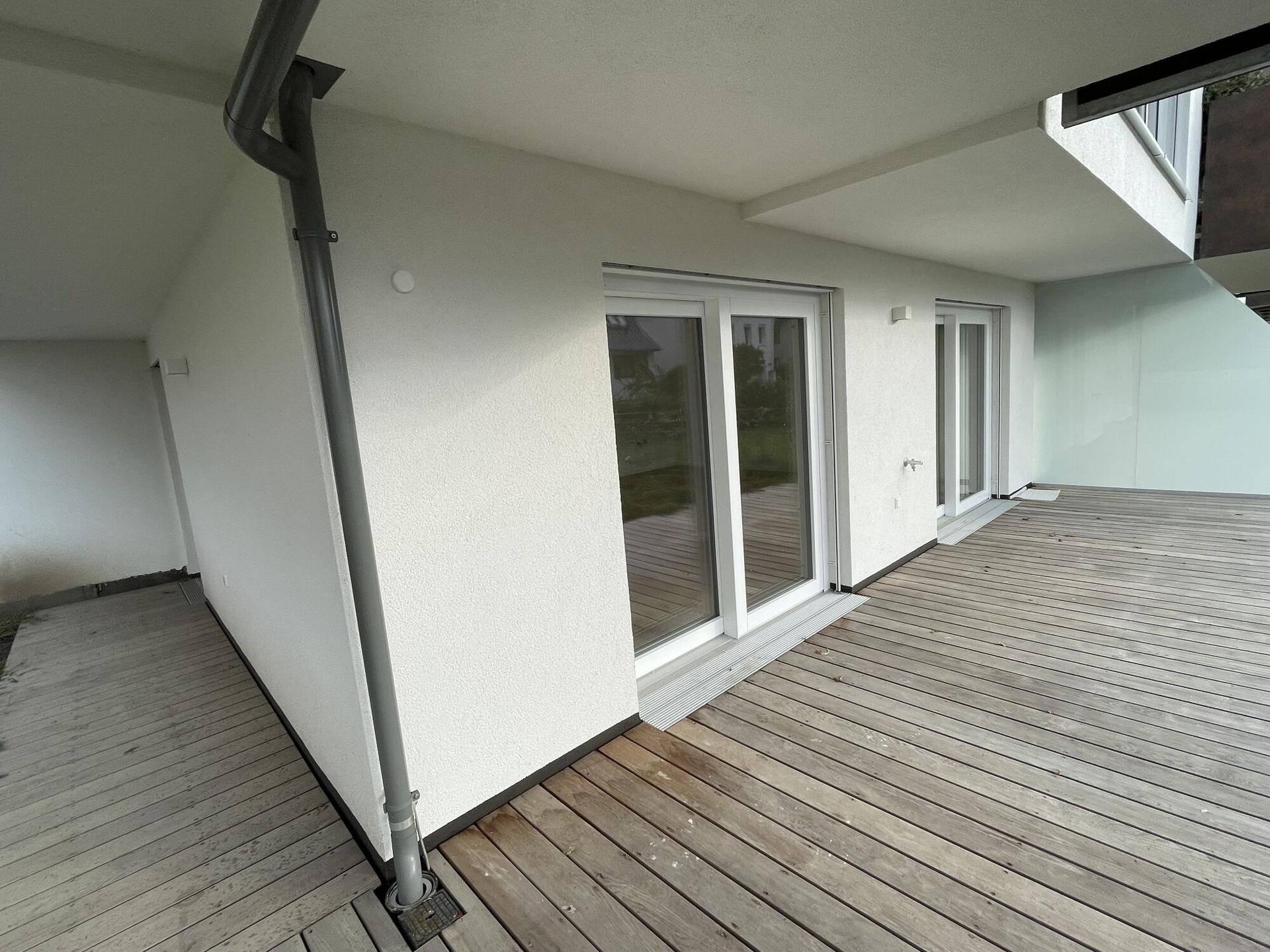 Geräumige Holzterrasse mit Zugang zu den Innenräumen, ideal für entspannte Stunden im Freien.