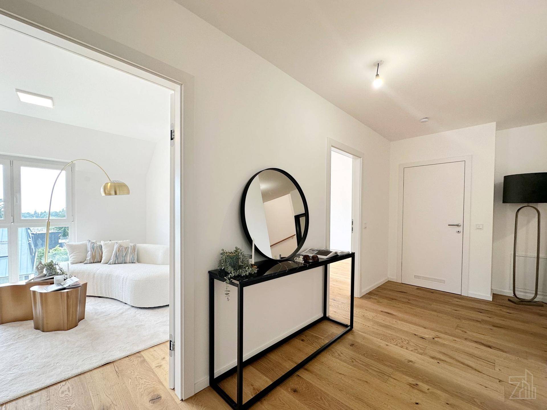 Heller Flur mit Holzboden, modernem Konsolentisch und Blick in den Wohnbereich.