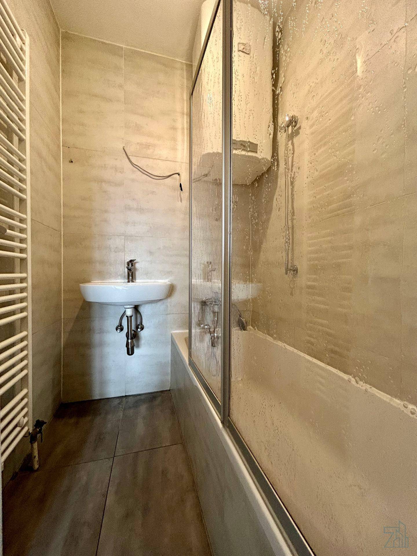 Modernes Badezimmer mit Badewanne, Duschwand, Waschbecken und beheiztem Handtuchhalter.
