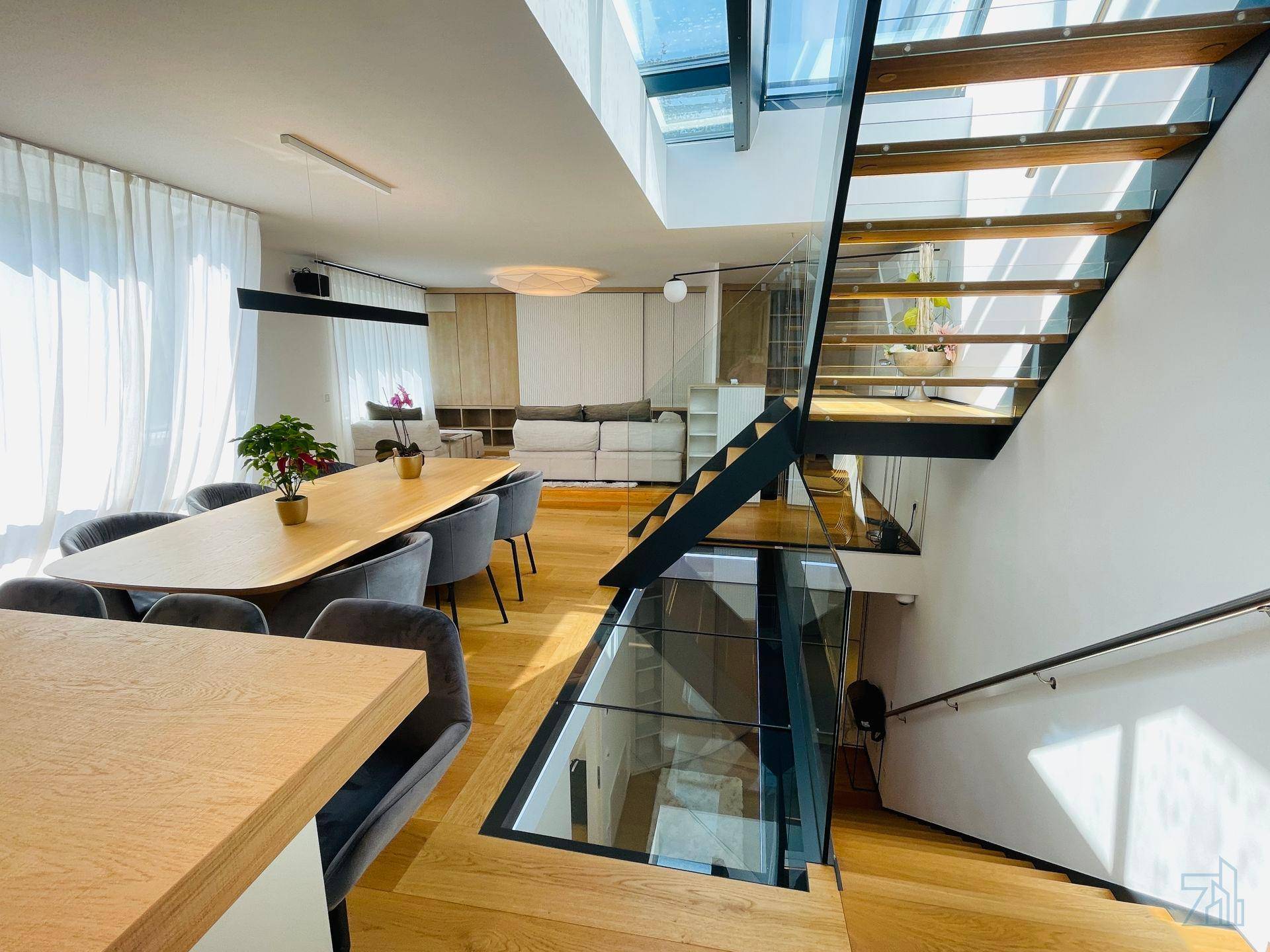Offener Wohn-Essbereich mit moderner Küche, eleganter Treppe und viel Tageslicht.