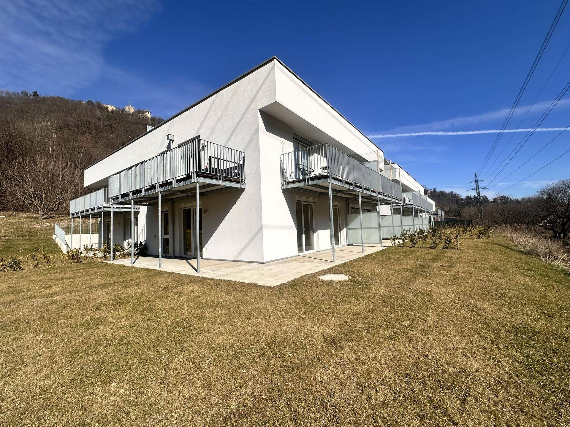 Moderne Wohnanlage mit Balkonen und großen Fensterfronten in grüner Umgebung.