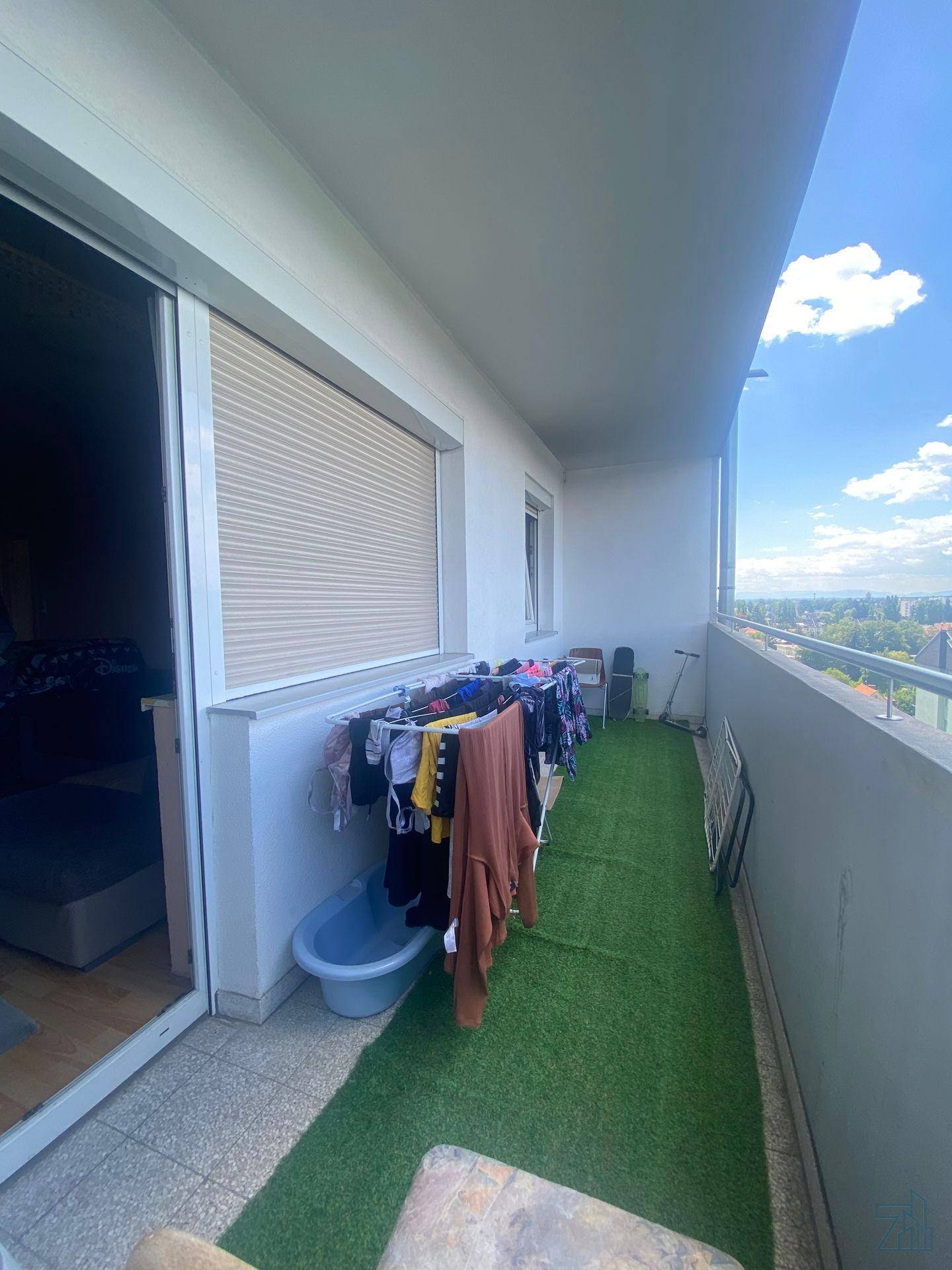Balkon mit Kunstrasen, Wäscheständer und Blick auf die Stadt.