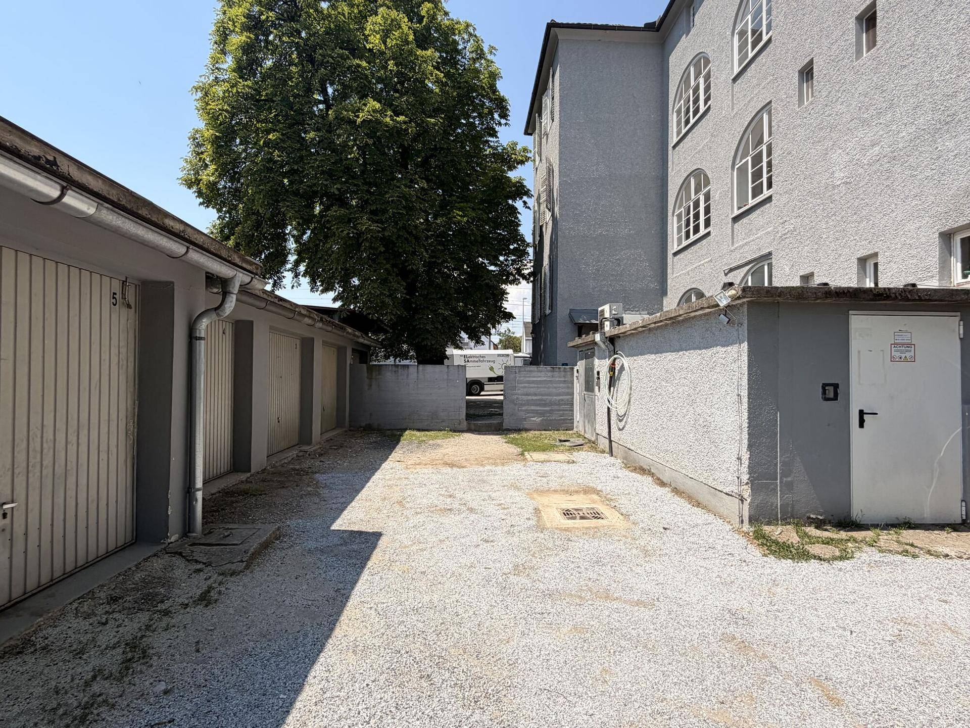Außenansicht des Gebäudes mit Garagenreihe und Schotterfläche im Vordergrund.