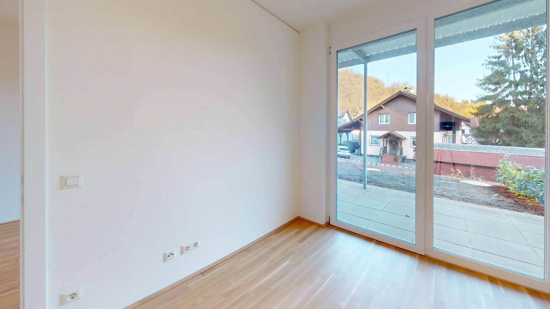 Heller Raum mit großen Fenstern und Zugang zu einem Außenbereich.