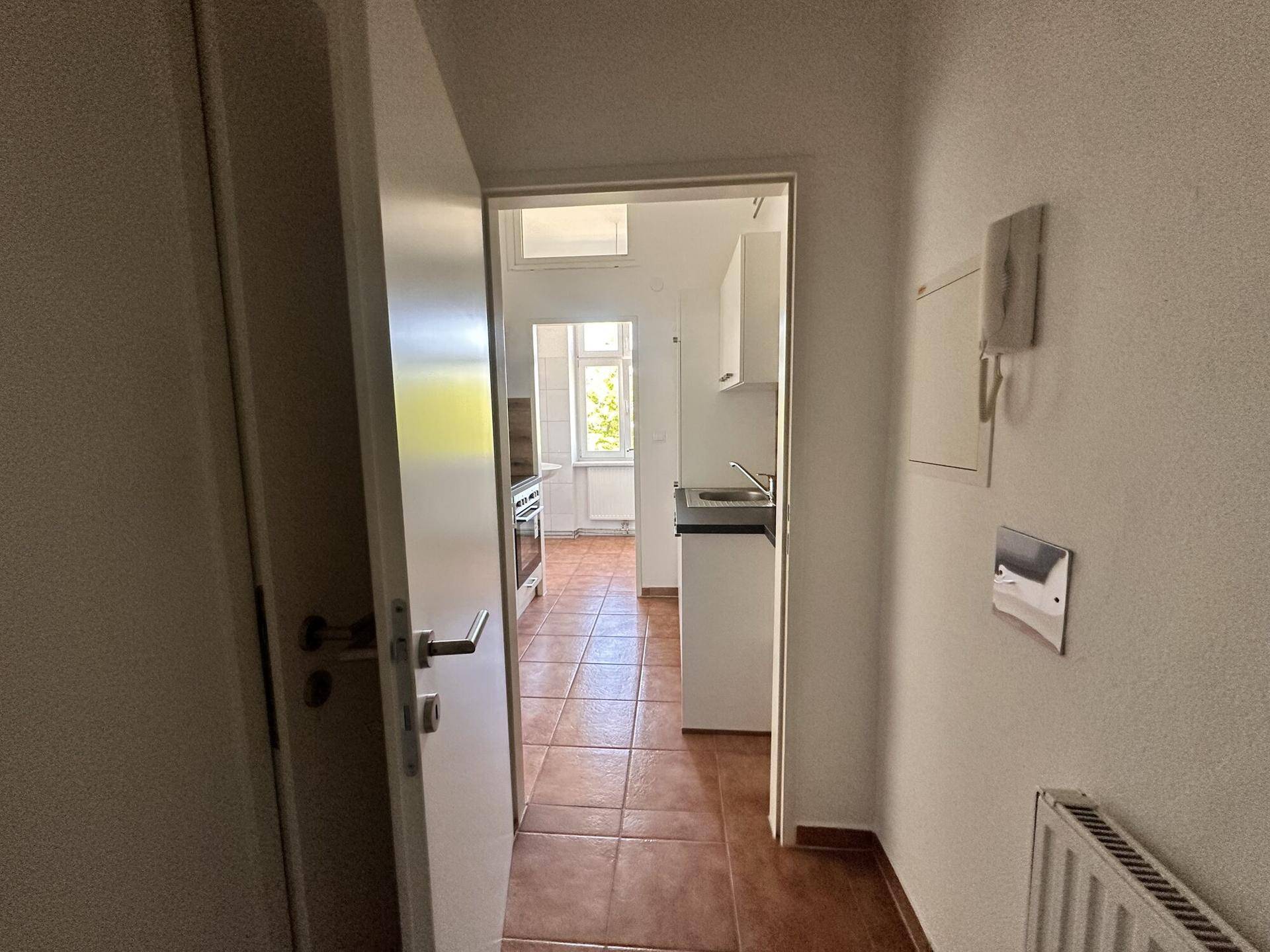 Flur mit Terrakotta-Fliesenboden und Gegensprechanlage, führt zur Küche.