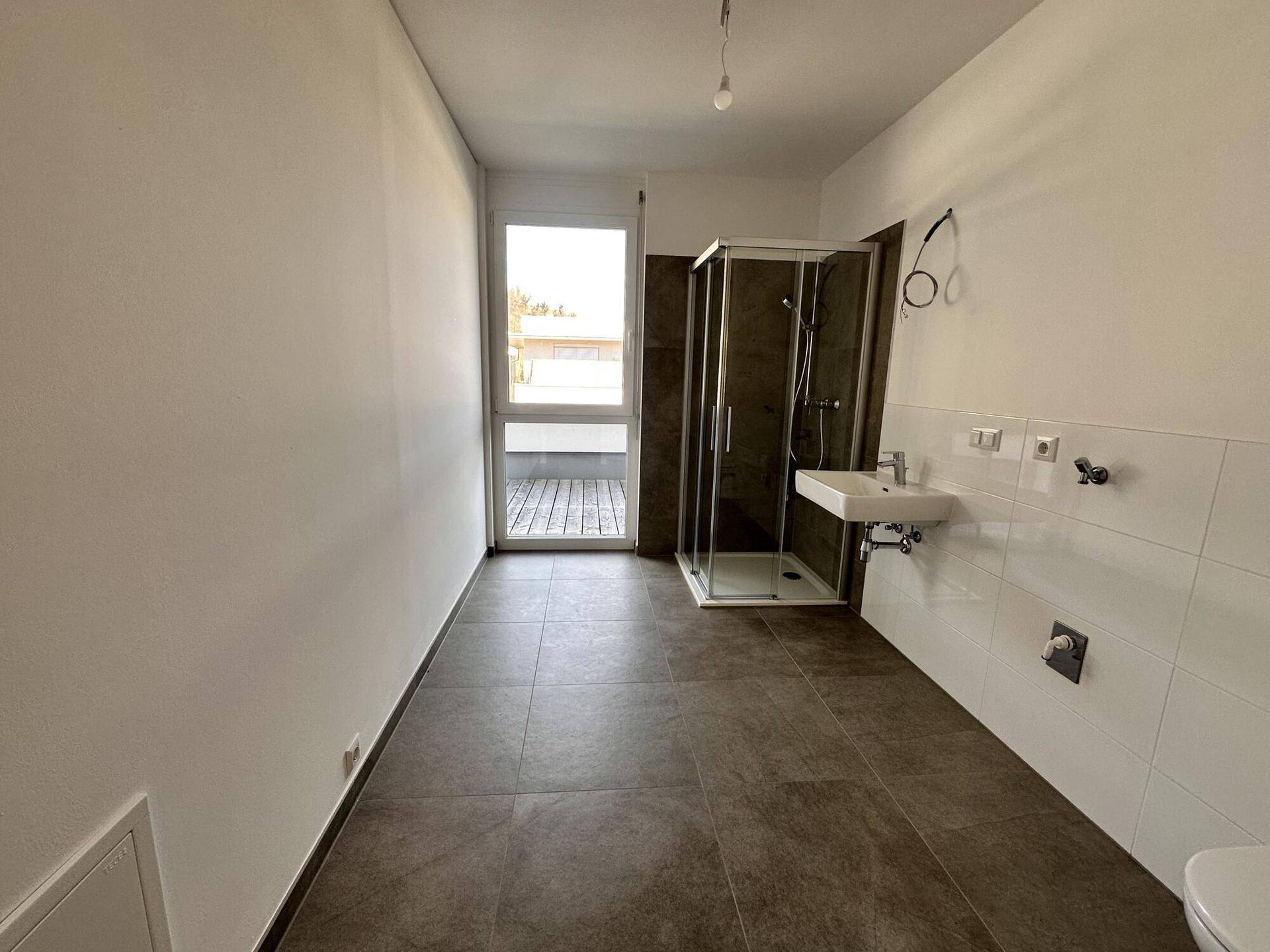 Modernes Badezimmer mit Duschkabine, Waschbecken und direktem Zugang zur Dachterrasse.