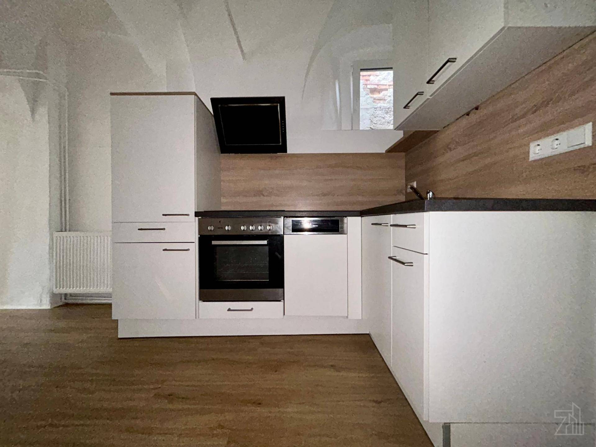 Moderne Einbauküche mit weißen Fronten, dunkler Arbeitsplatte und Holzwandverkleidung.