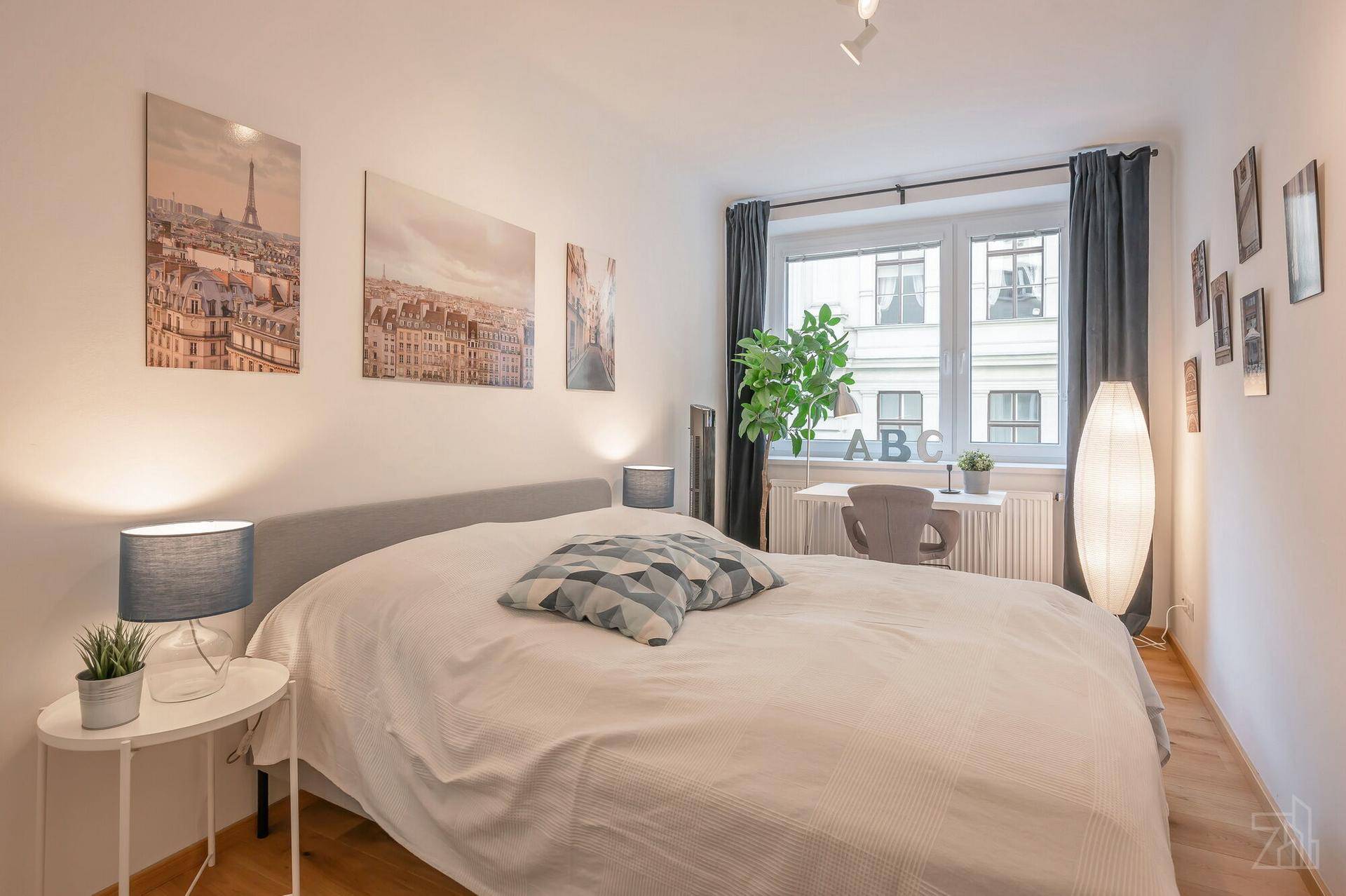 Helles Schlafzimmer mit Doppelbett, Schreibtisch am Fenster und stilvoller Wanddekoration.