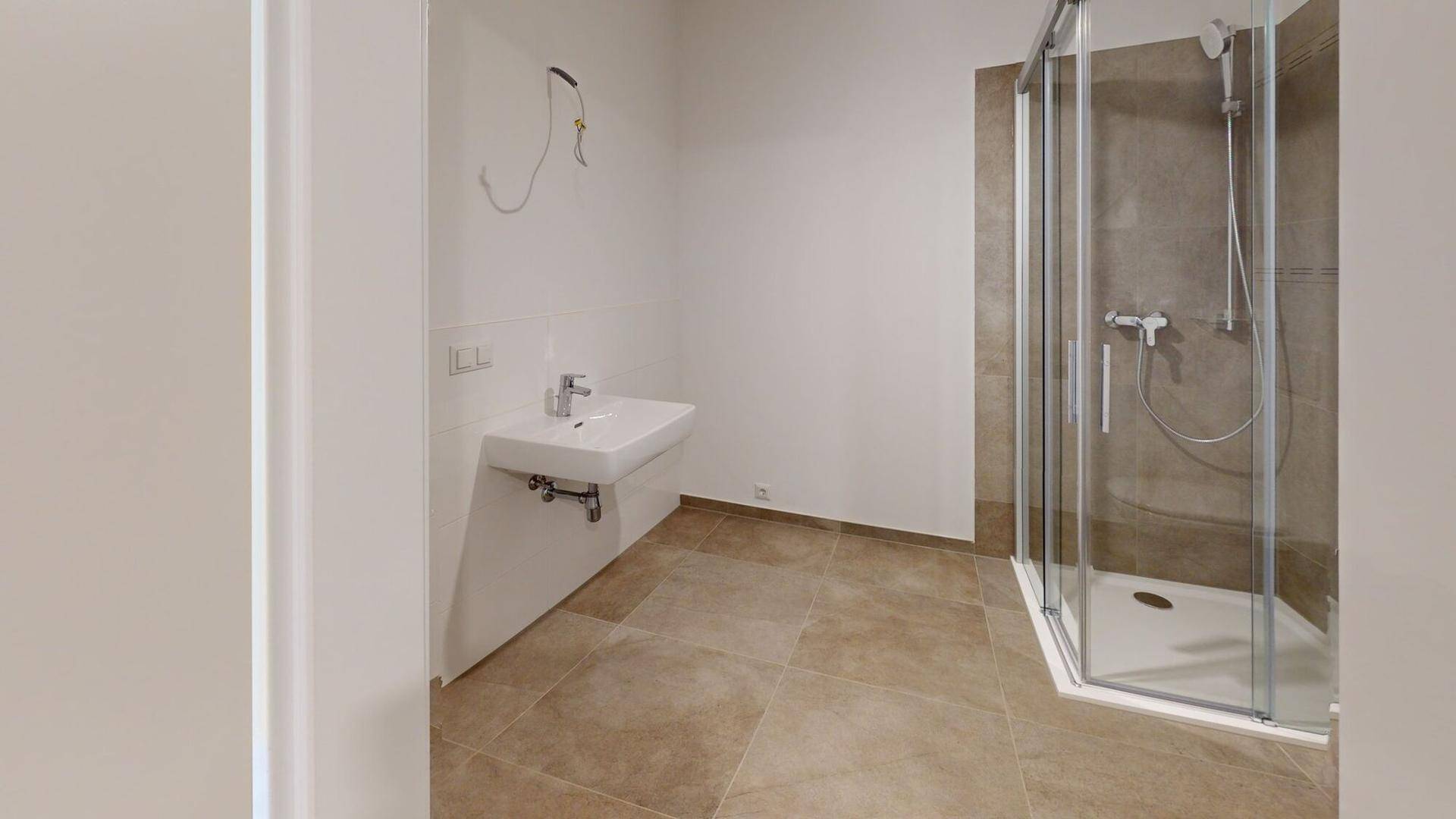 Modernes Badezimmer mit großformatigen Fliesen, Waschbecken und Duschkabine.