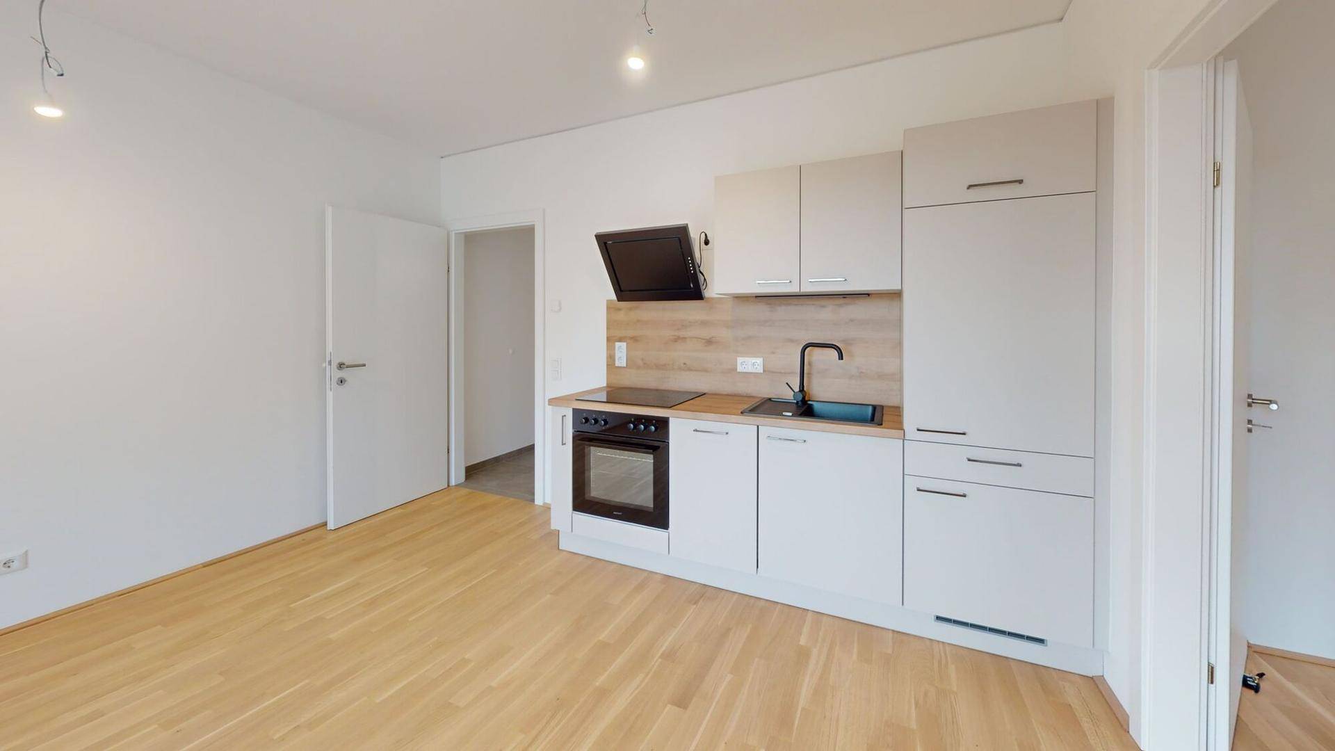 Helle Küchenzeile mit modernen weißen Schränken und Holzdetails in einem offenen Wohnbereich.