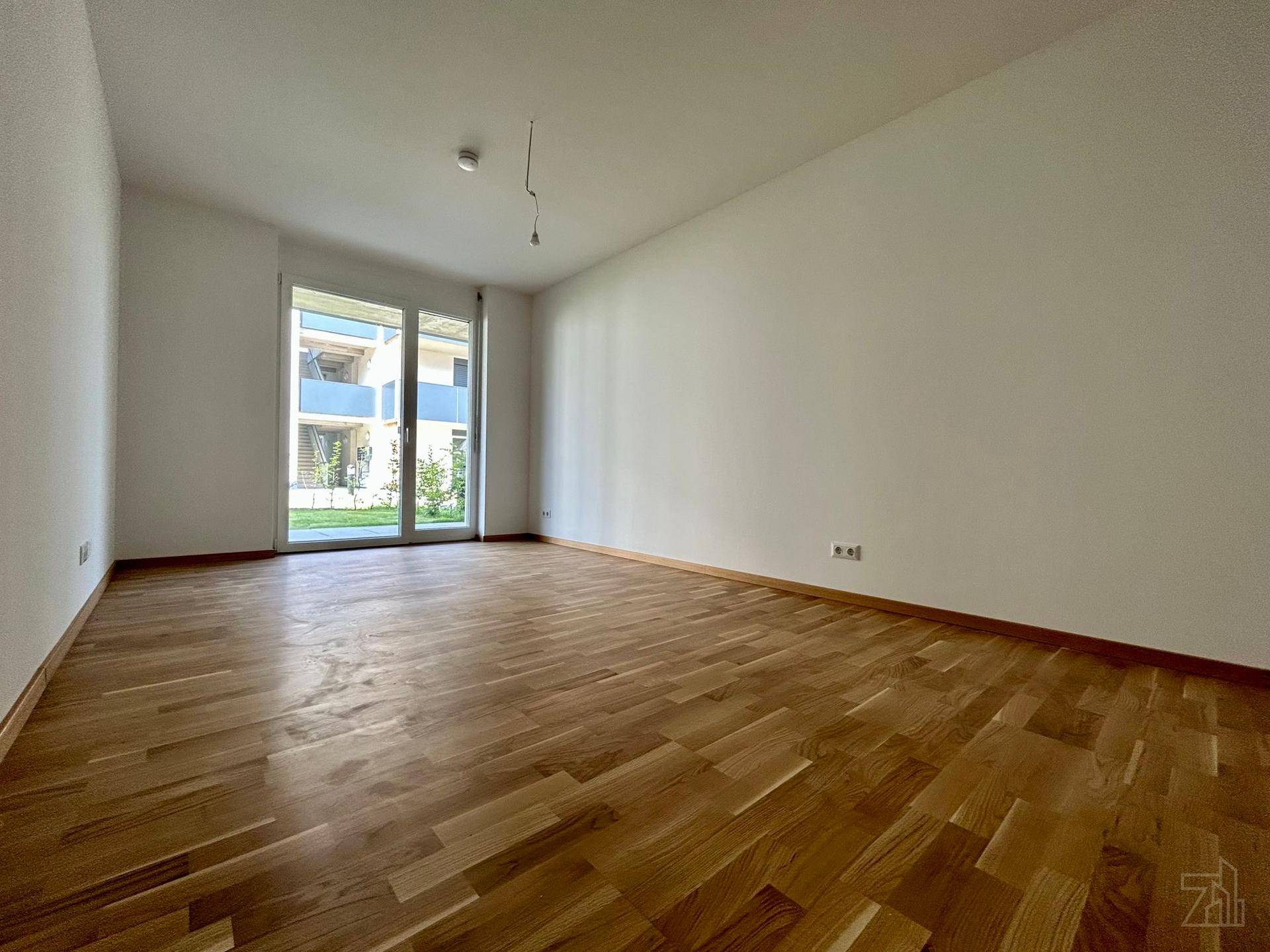 Helles Schlafzimmer mit Parkettboden und Zugang zu einem Balkon oder einer Terrasse.