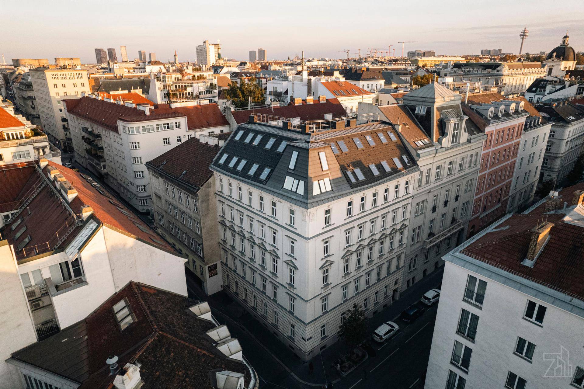 Historisches Stadtviertel mit prächtigen Altbauten und traditionellen Dächern unter strahlendem Sonnenschein.