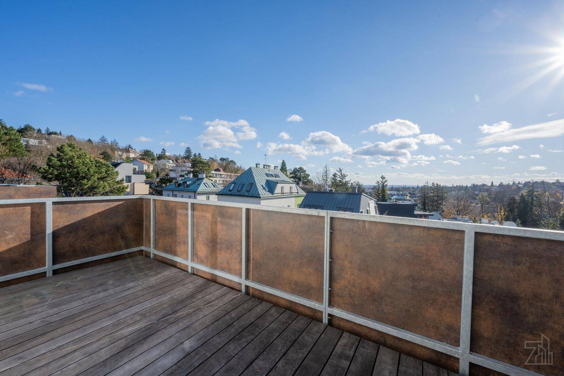 Sonniger Balkon mit Holzboden, modernem Geländer und weitem Blick über die Stadt.