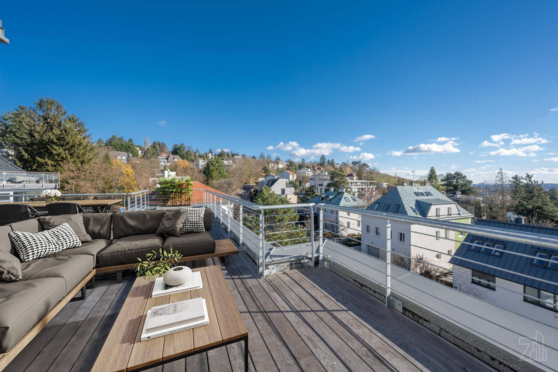 Große möblierte Dachterrasse mit Holzboden, Metallgeländer und weitem Blick über die Umgebung.