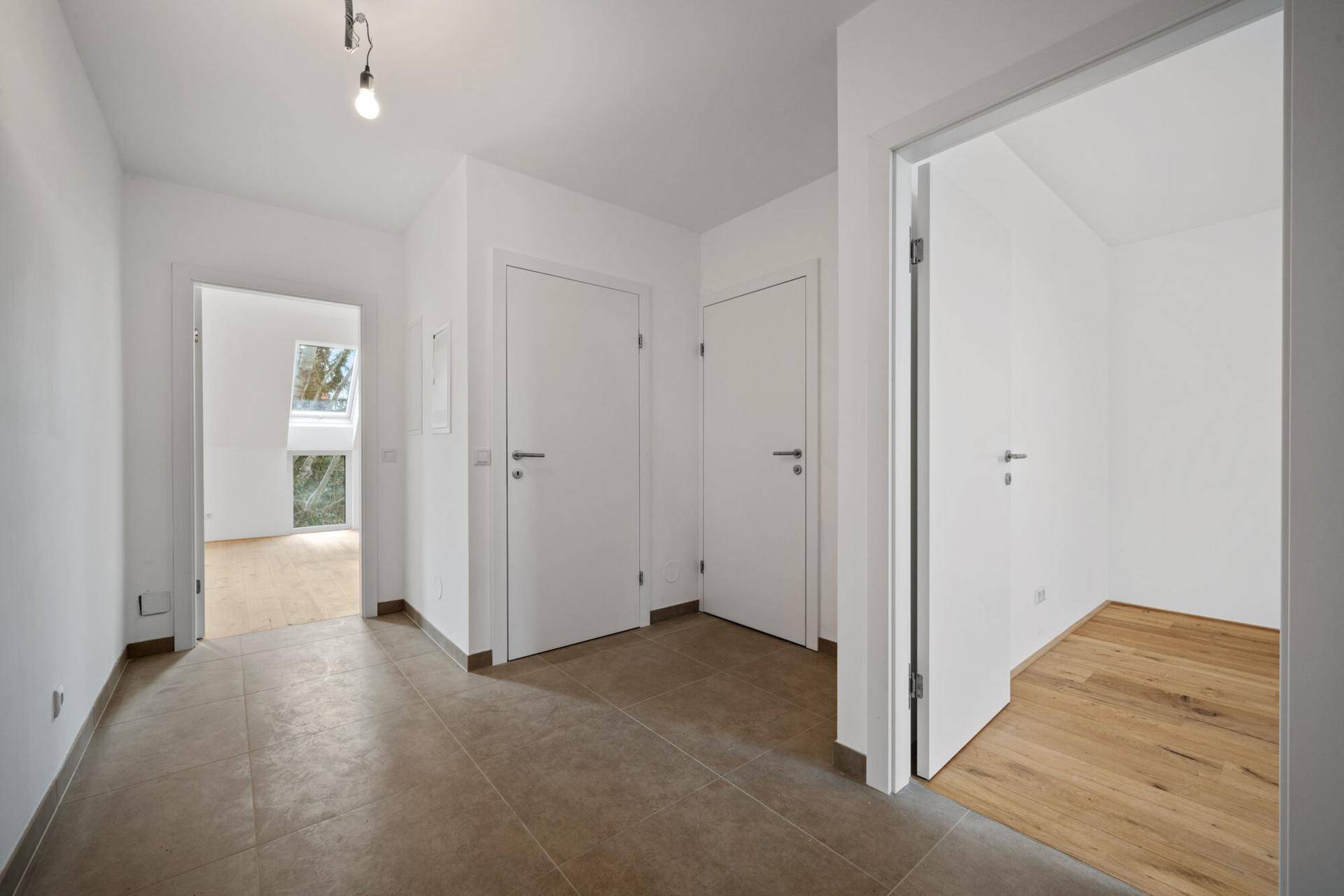 Heller Flur mit Fliesenboden und Zugang zu verschiedenen Zimmern, inklusive Blick in einen weiteren Raum.