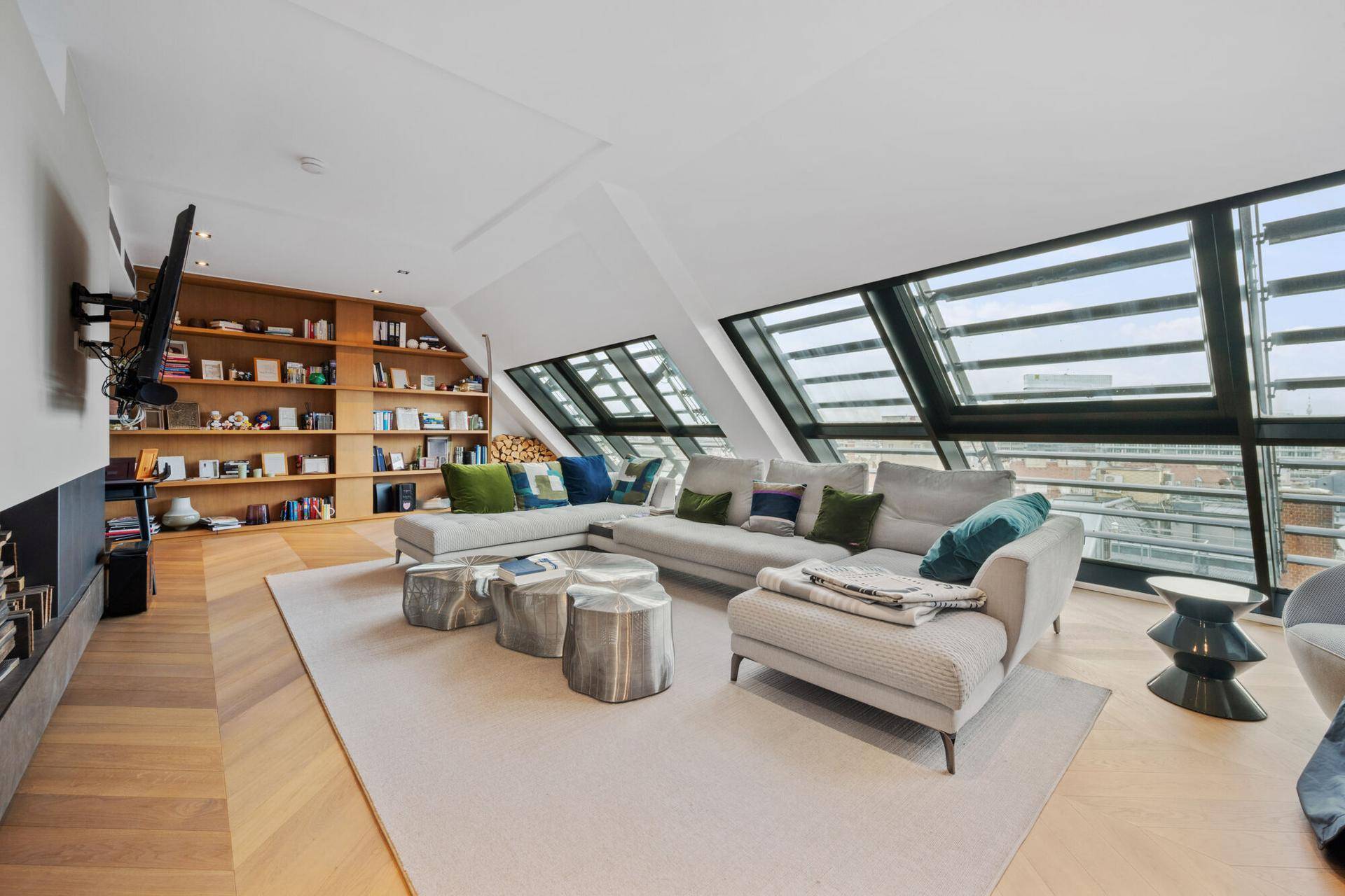 Modernes Wohnzimmer mit großem Sofa, Bücherregal und Fernseher an der Wand.
