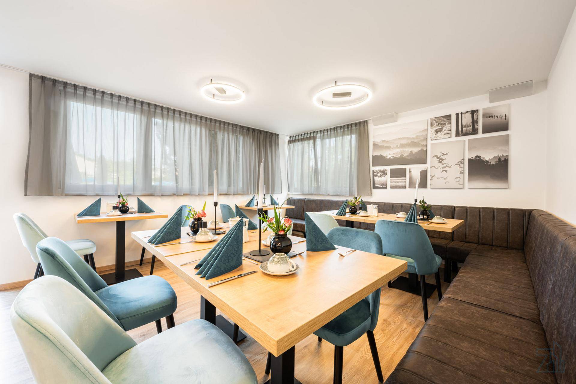 Gemütlicher Speisesaal mit elegant gedeckten Tischen, bequemen Stühlen und einer langen Sitzbank.