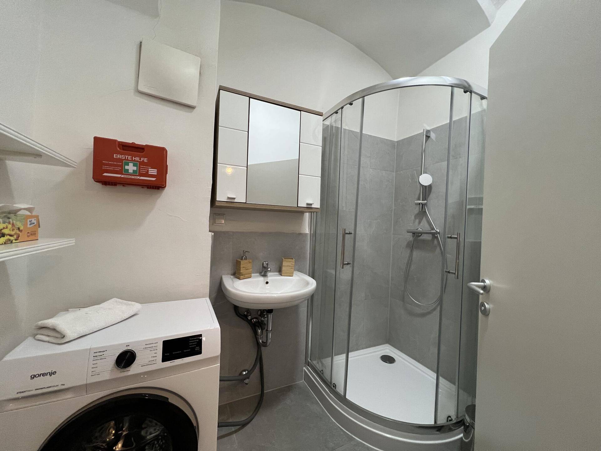Modernes Badezimmer mit Duschkabine, Waschbecken und Waschmaschine.