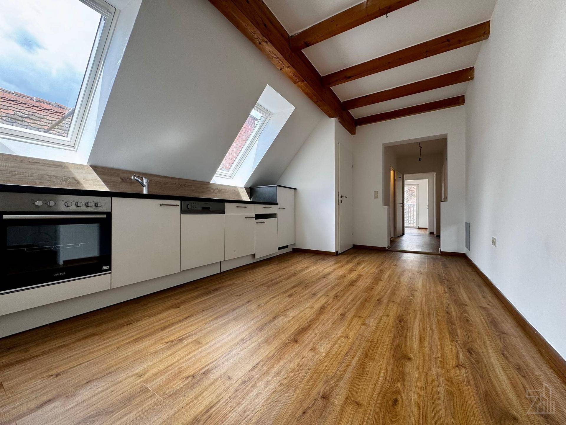 Moderne Küche im Dachgeschoss mit Holzbalken, Dachfenstern und Laminatboden.