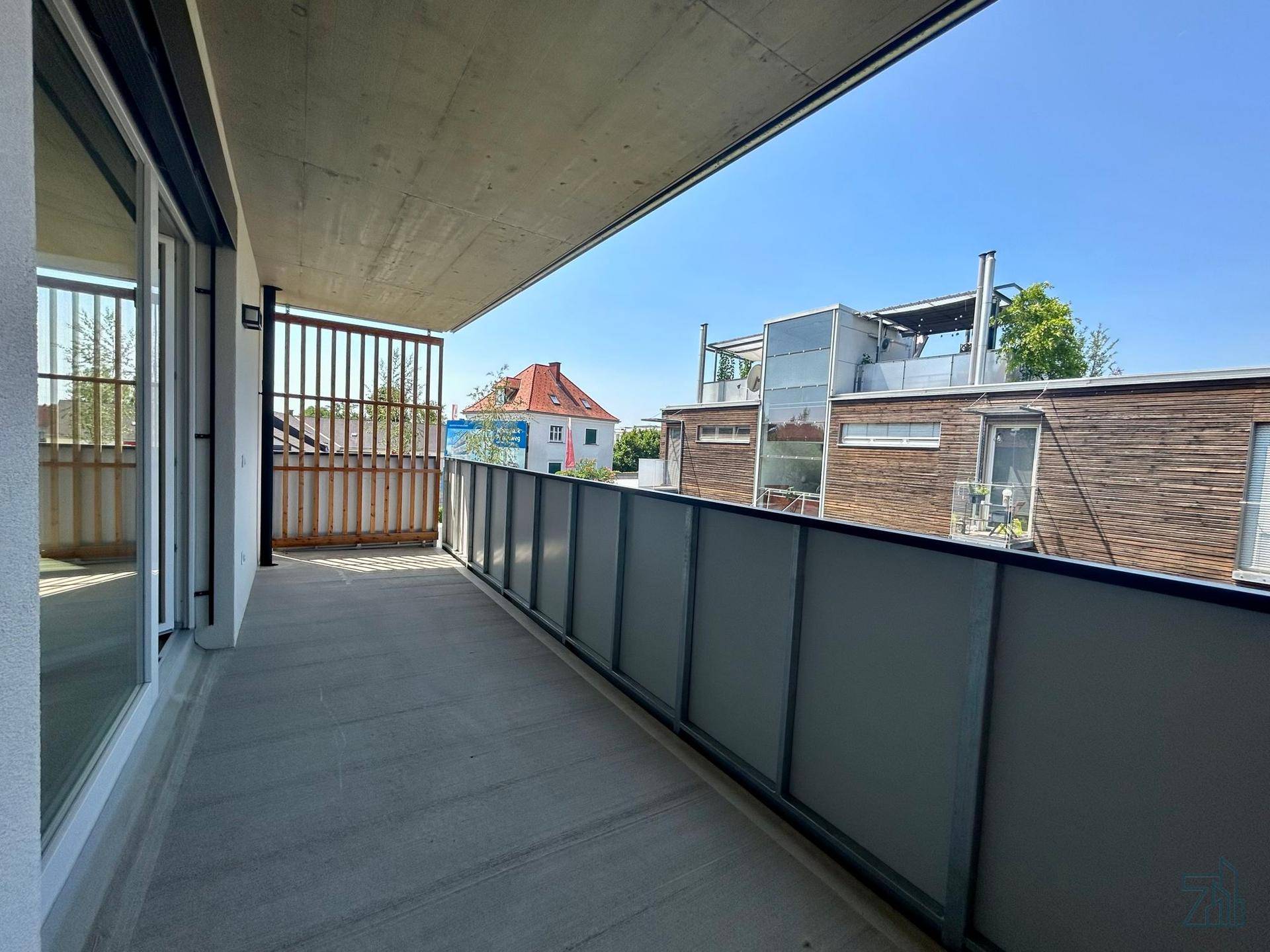 Langer Balkon mit moderner Glasbrüstung und Blick auf die umliegenden Gebäude.