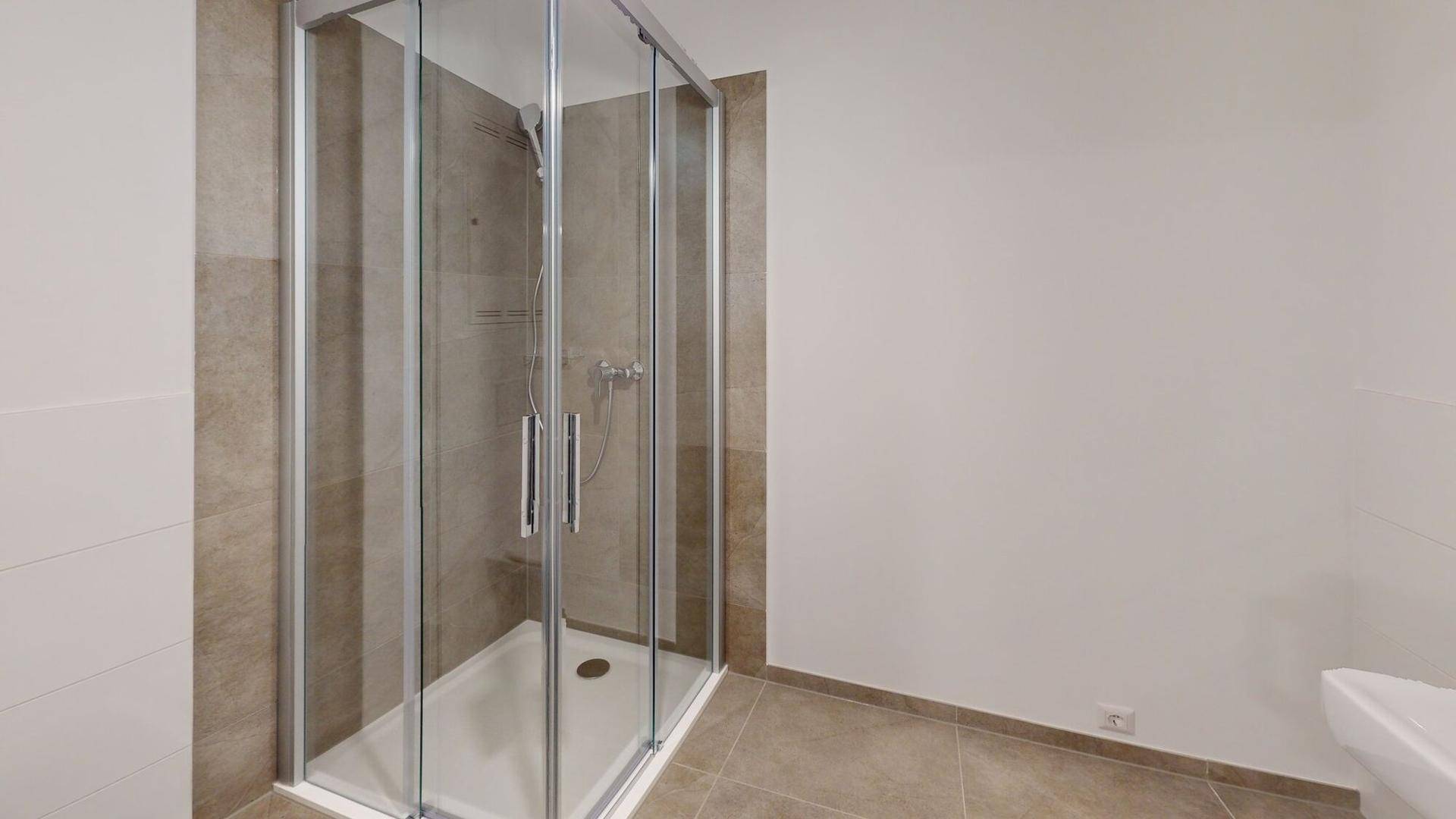 Modernes Badezimmer mit Duschkabine, hellen Fliesen und weißer Keramik.