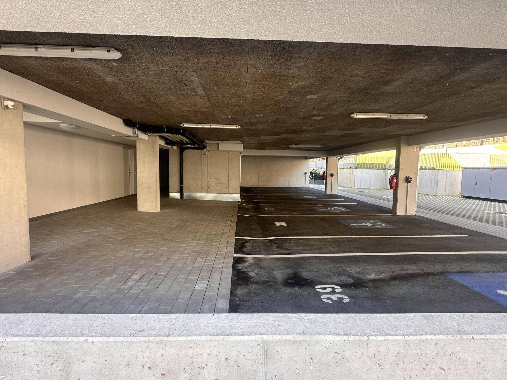 Geräumige Tiefgarage mit markierten Parkplätzen und barrierefreien Stellflächen.