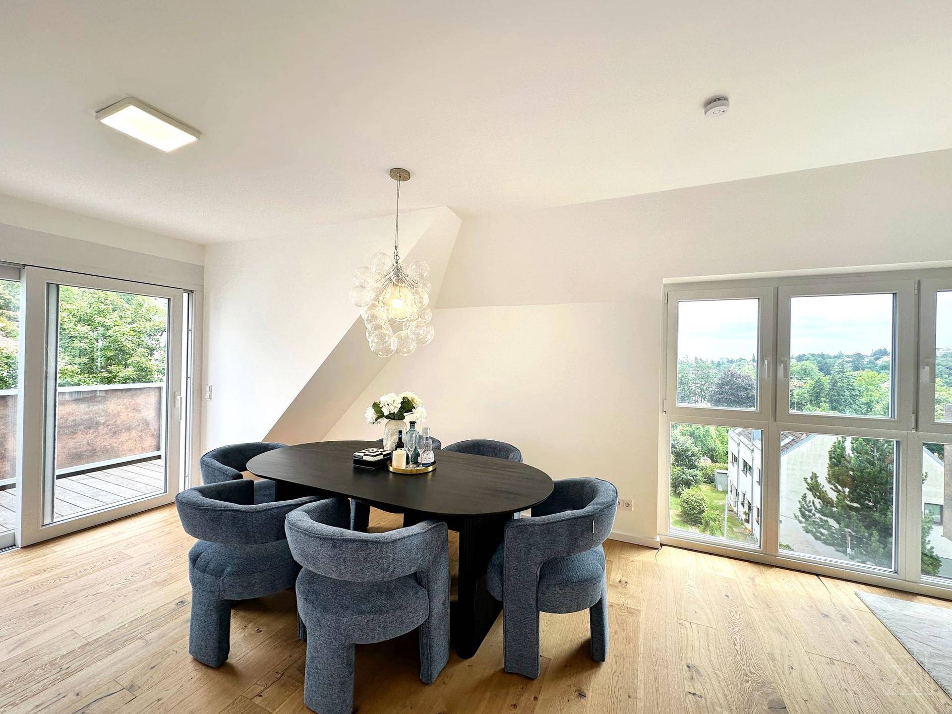 Heller Essbereich mit Holzboden, modernem Esstisch, Designerleuchte und Zugang zum Balkon.
