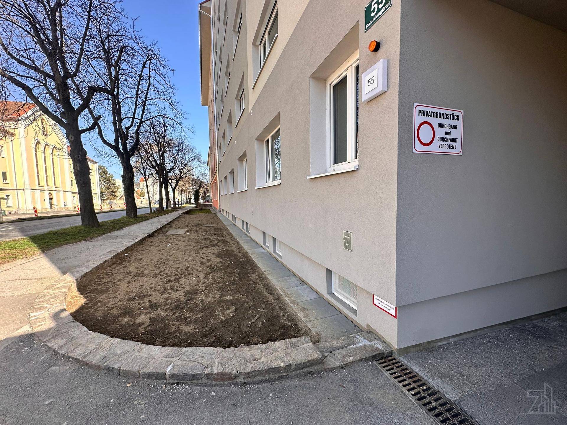 Seitenansicht des Wohngebäudes mit Grünstreifen und Durchgang zum Innenhof.