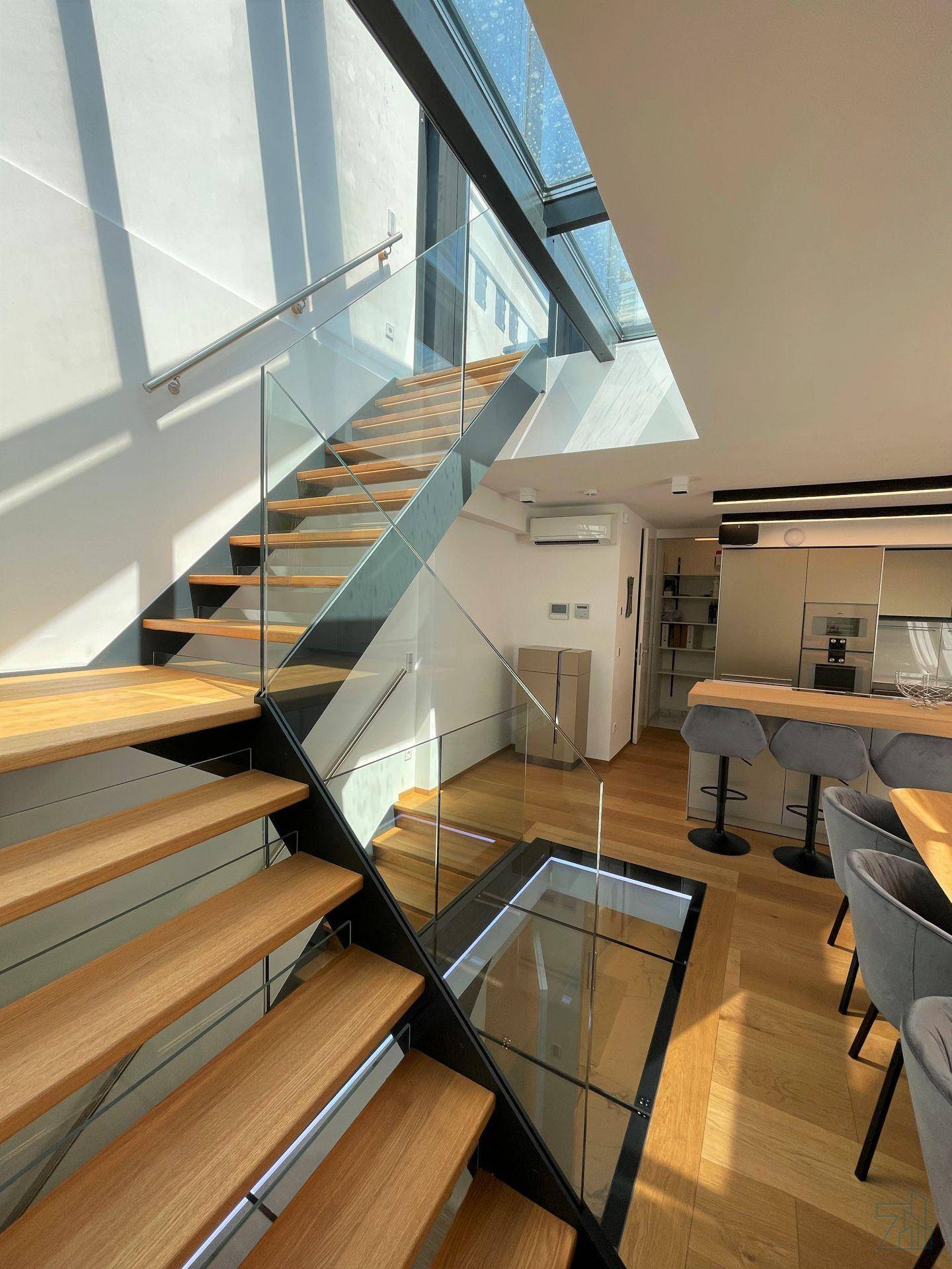 Blick von der oberen Treppe auf den offenen Wohn- und Küchenbereich mit viel Tageslicht.