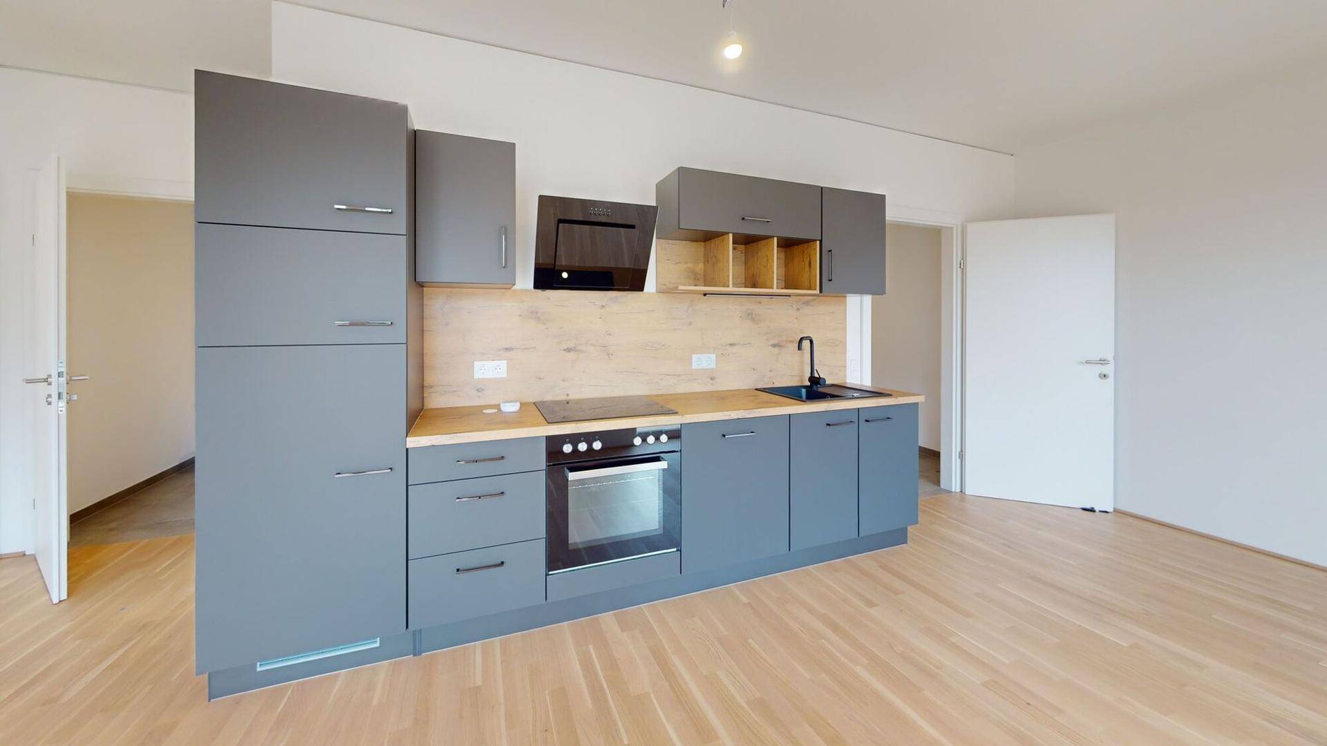 Moderne Einbauküche in Grau mit Holzdetails, Induktionskochfeld und integriertem Backofen.