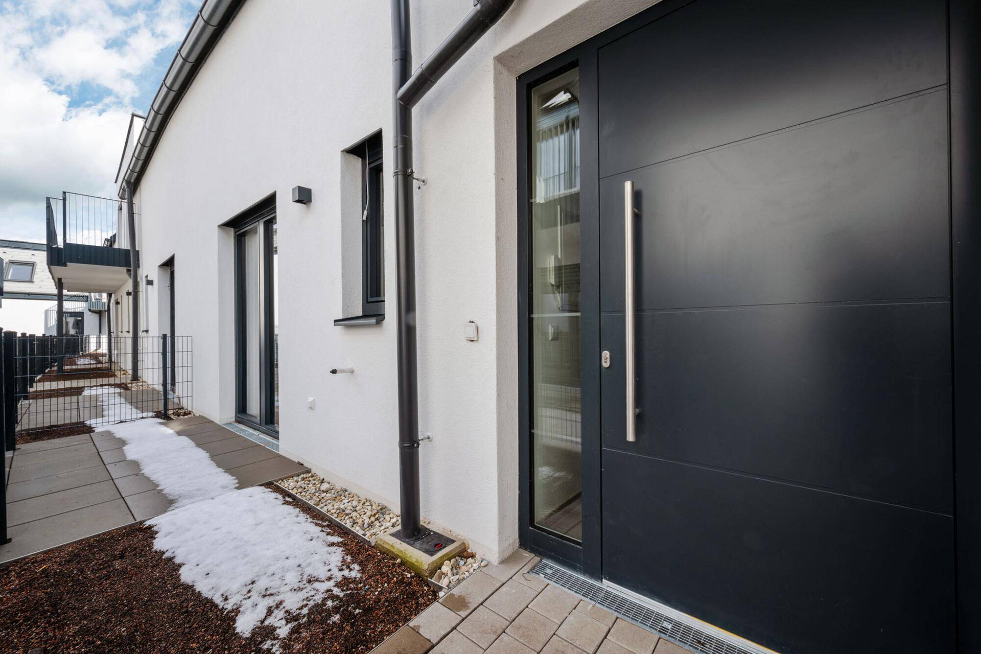 Moderne Eingangstür in dunklem Anthrazit an einer weißen Hausfassade.